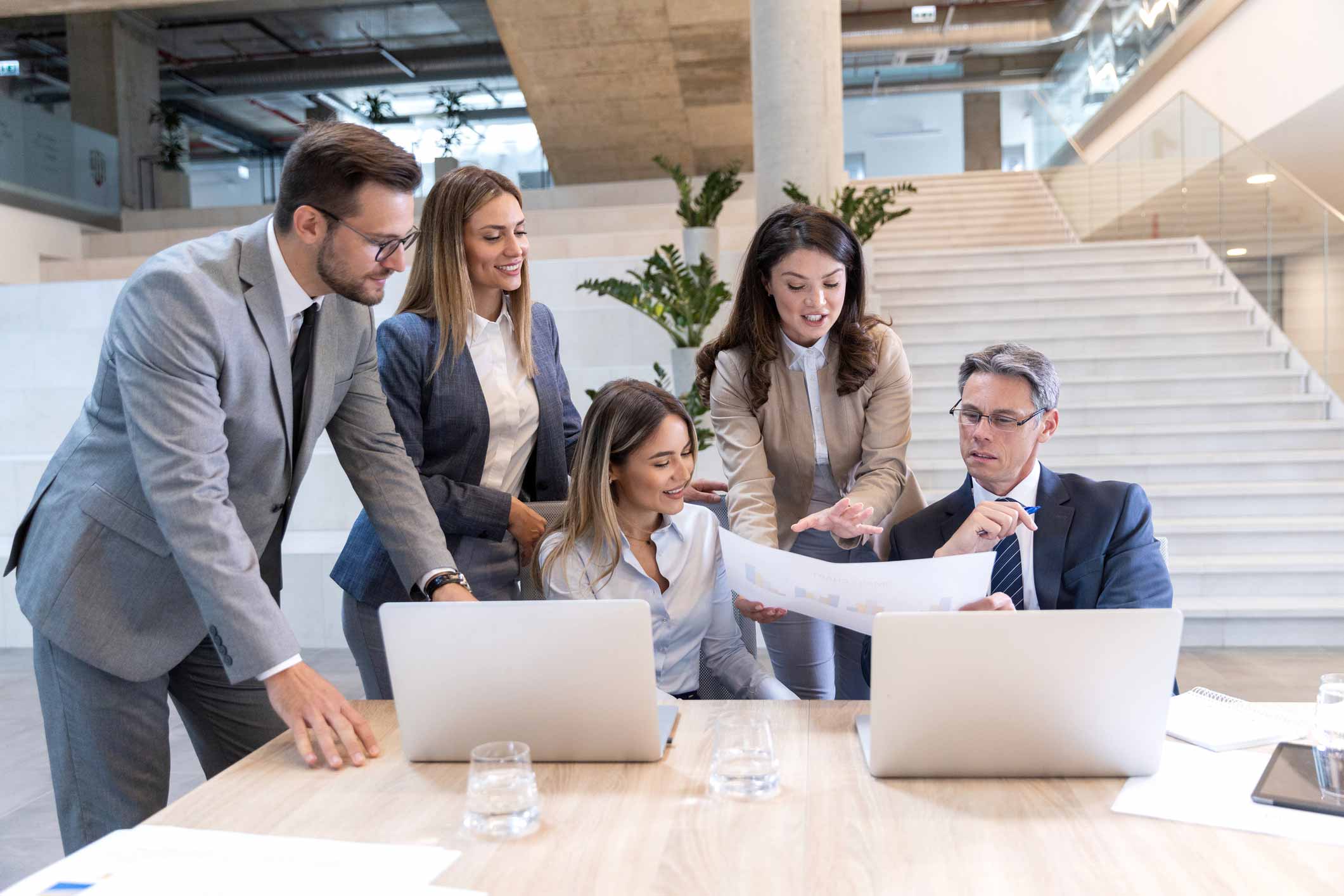 Five business professionals use AI Legal Document Analysis Technology while collaborating in office.