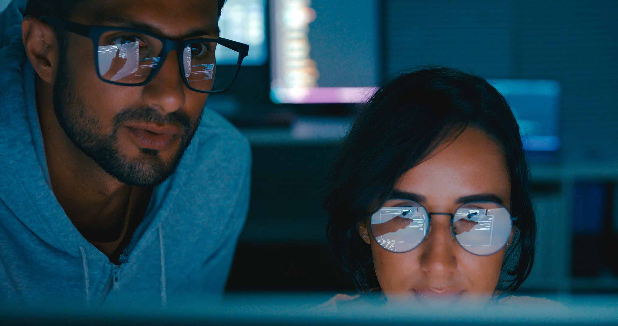 Two people in glasses review ransomware negotiation and network remediation strategies onscreen.