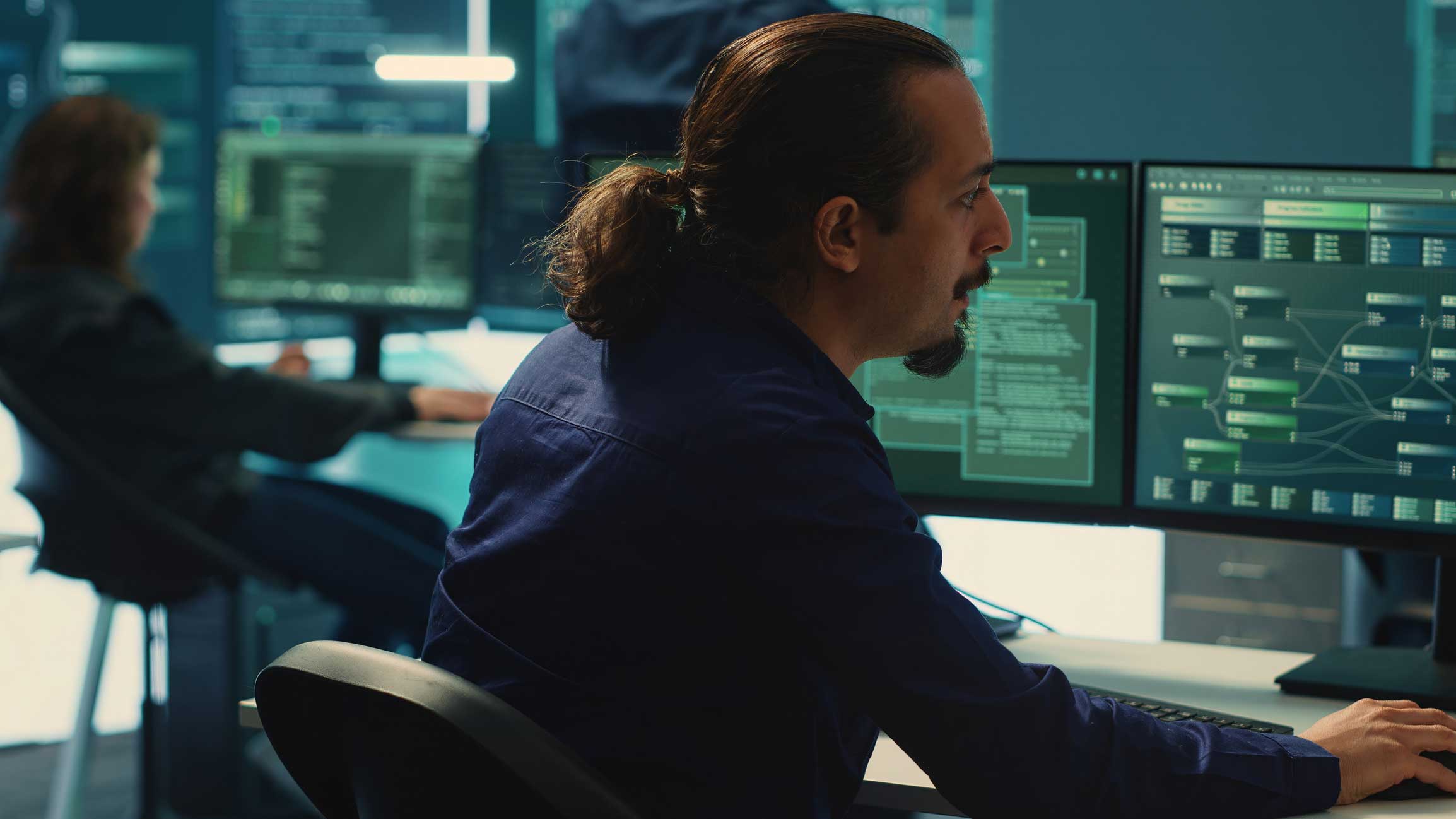 Man analyzing Ransomware Negotiation and Remediation data on screens in a modern office setting.
