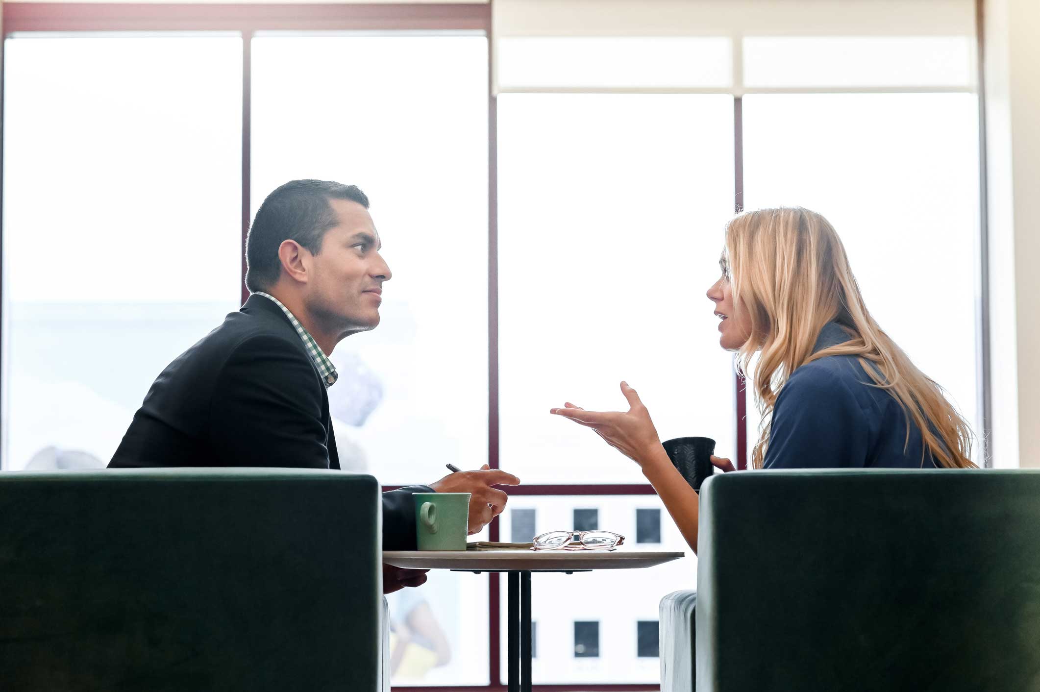 Two people discuss cybersecurity consulting in a bright, modern office setting.