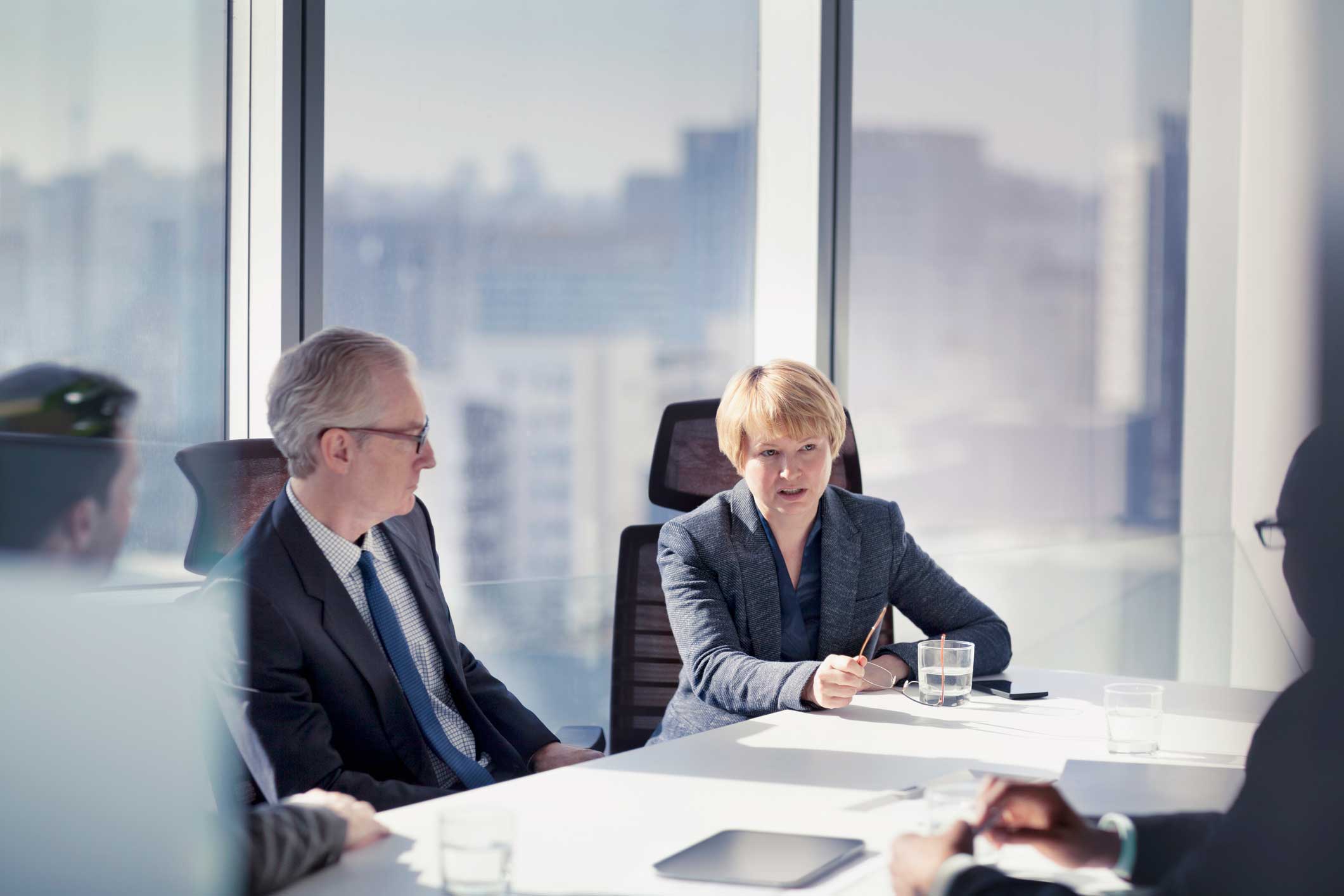 Four people in business attire meet at a Machine Learning Consulting Firm’s bright office table.