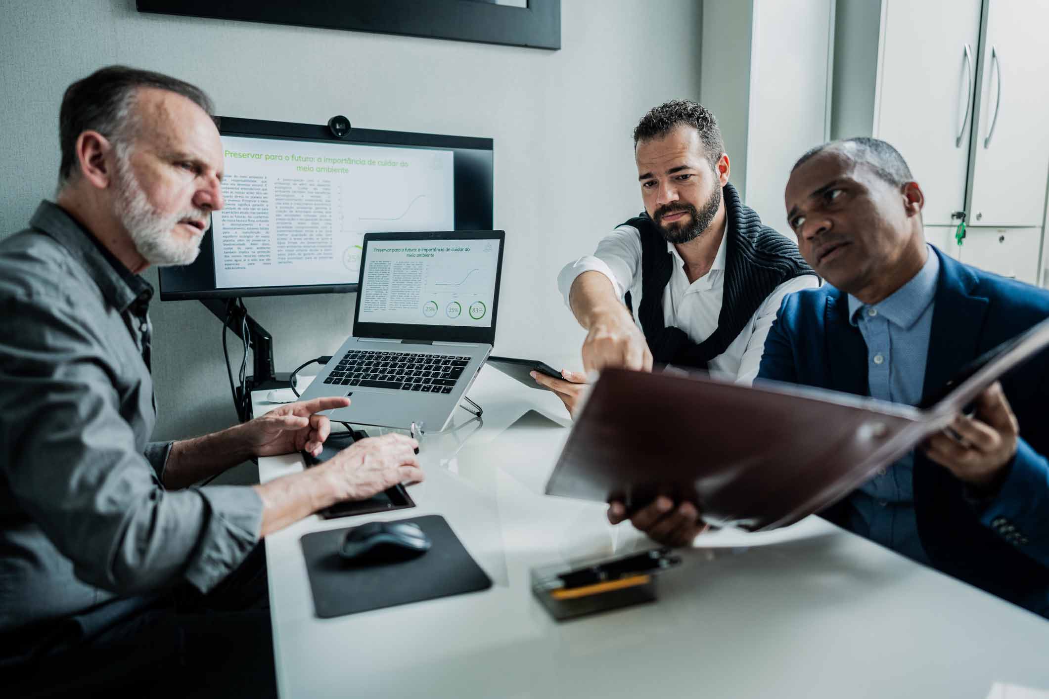Three men in a meeting review data with guidance from data breach consulting firms.