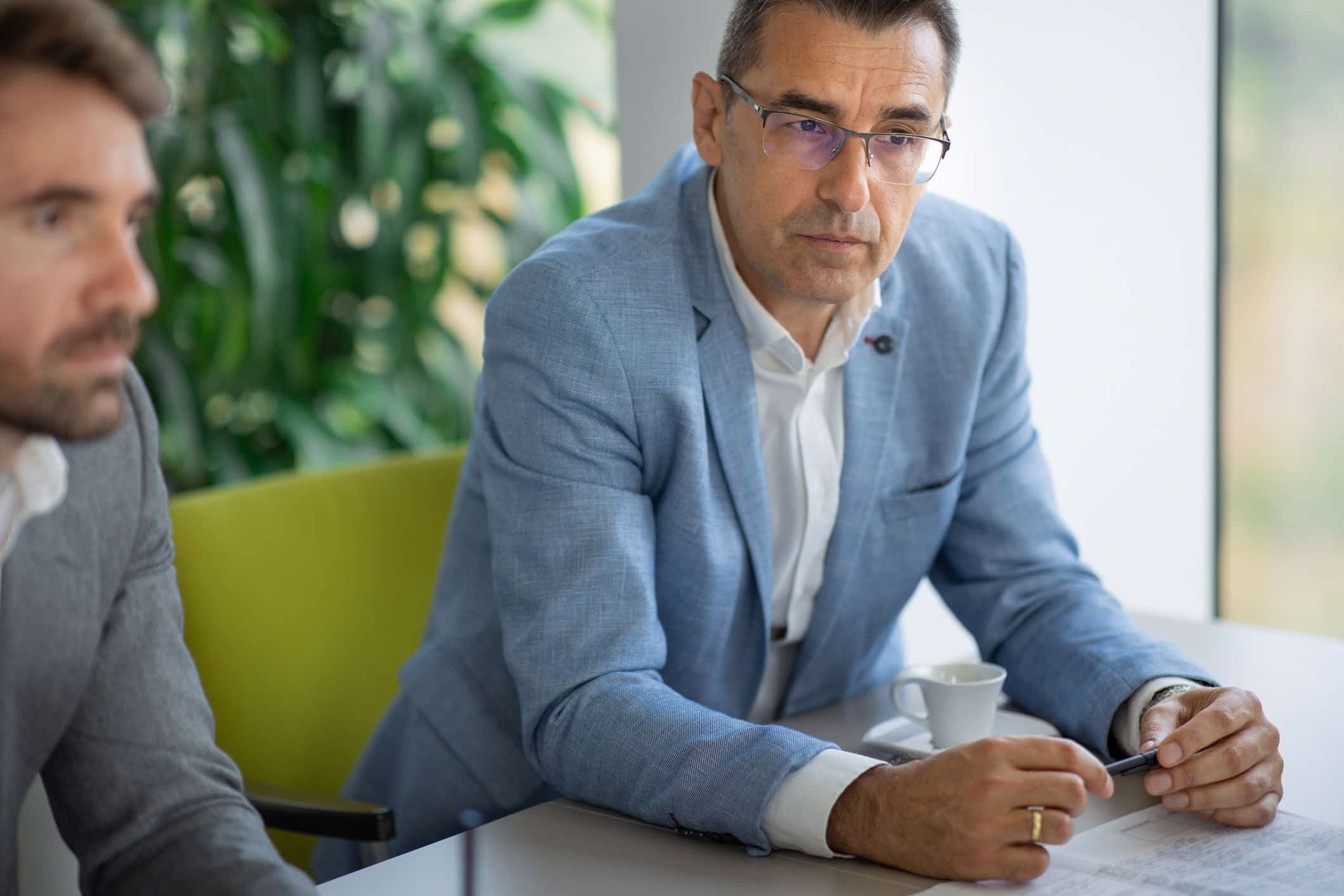 Two men in business suits discuss papers, exploring Risk Management Consulting Services.