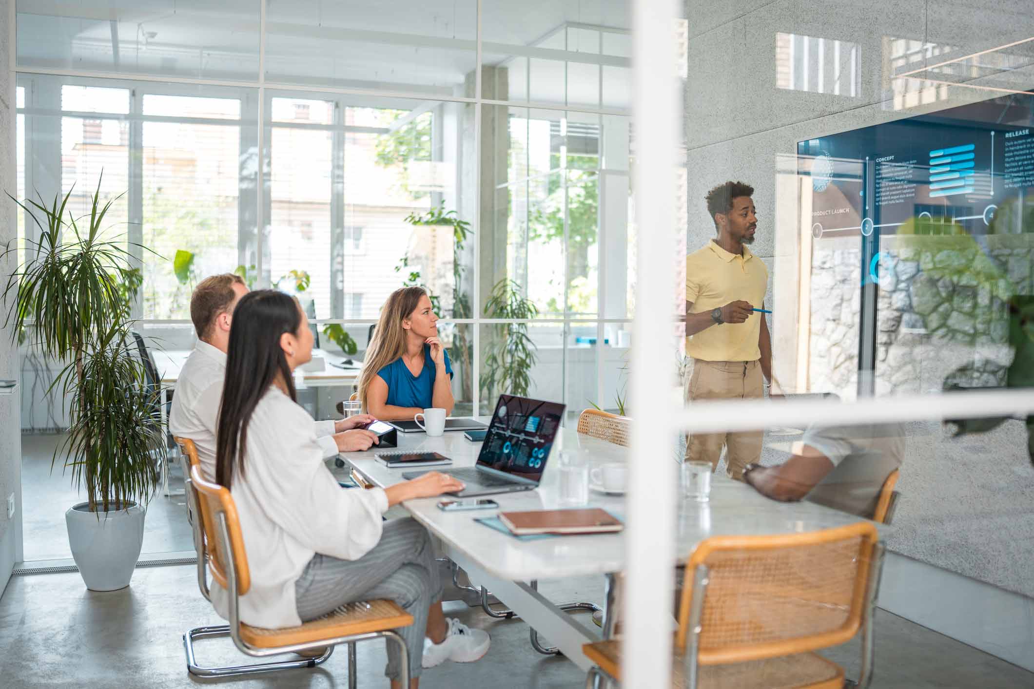 Four people in a meeting room watch a man present cyber incident response planning data.