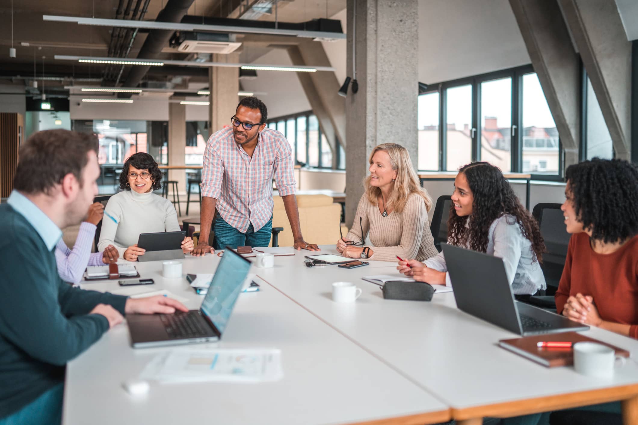 A diverse group discusses TAR Strategy around a conference table in a modern office.