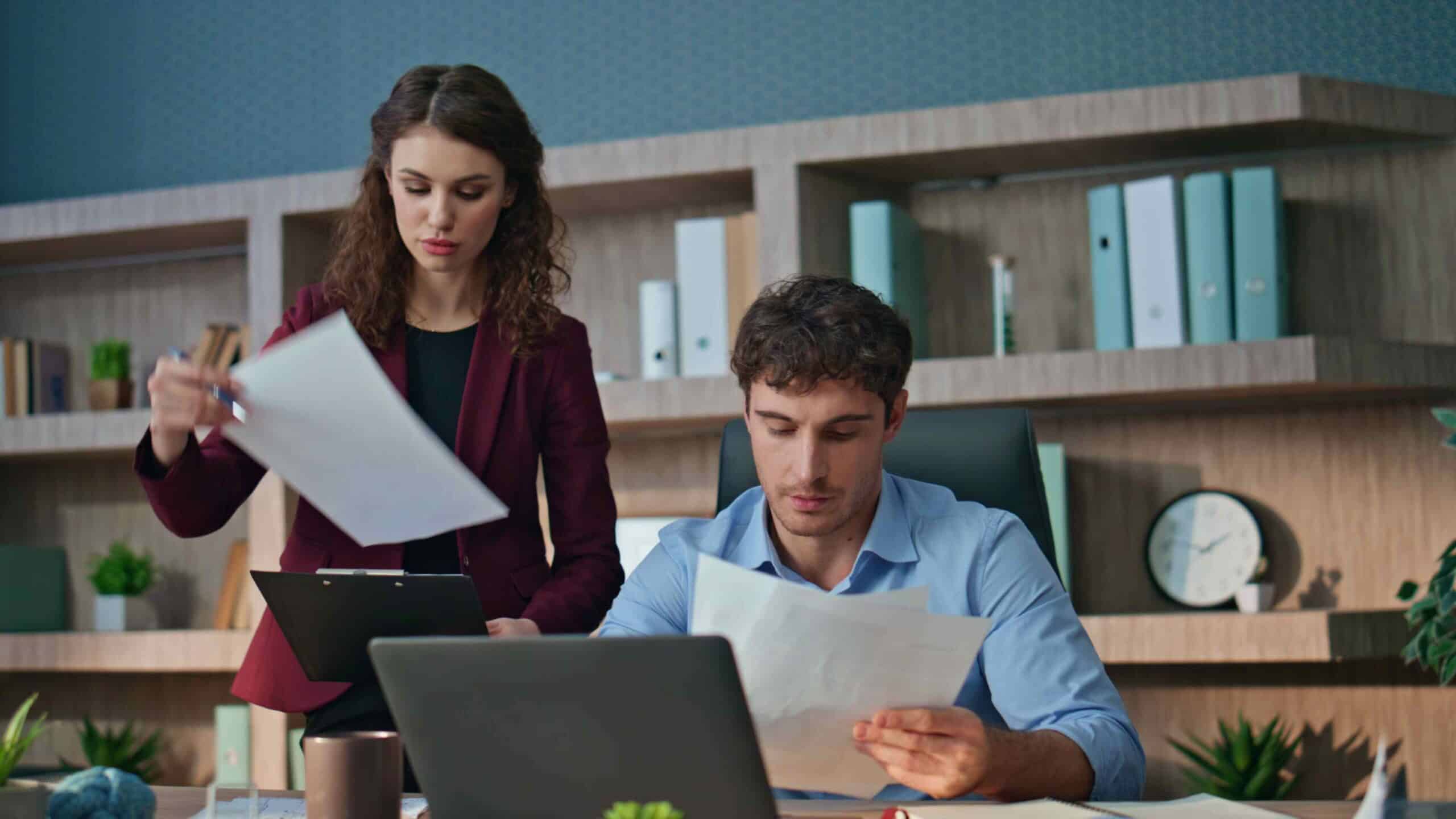 Two Continuous Active Learning Consultants review documents together at a desk with a laptop.