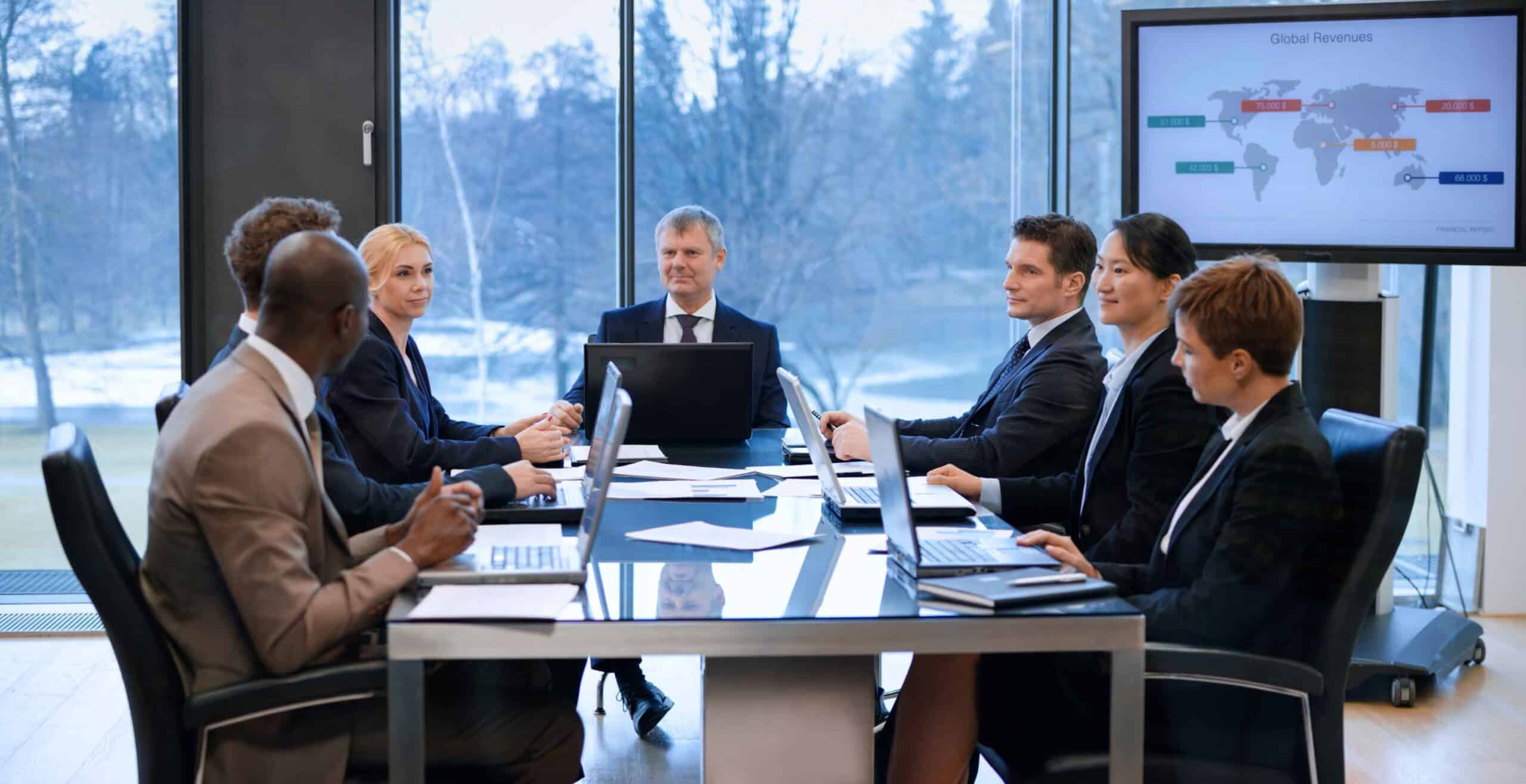 Eight business professionals and mobile device management consultants in a meeting room.