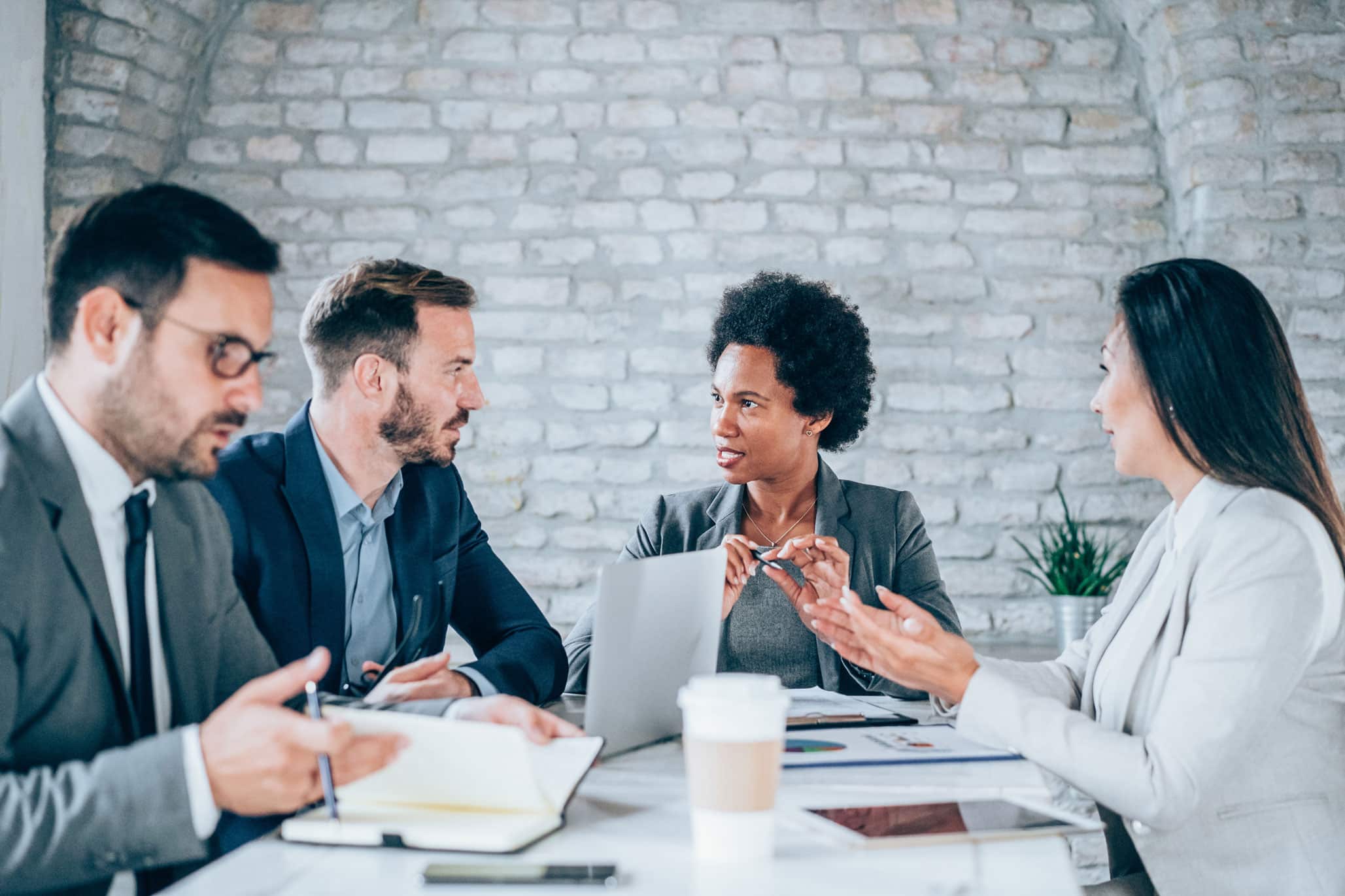 Four business professionals discuss Real-Time Analytics Consulting Services in a modern office.