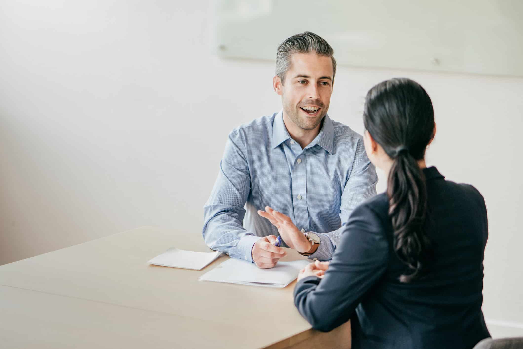 Two people discuss Scenario-Based Resource Planning at a desk in a bright office setting.