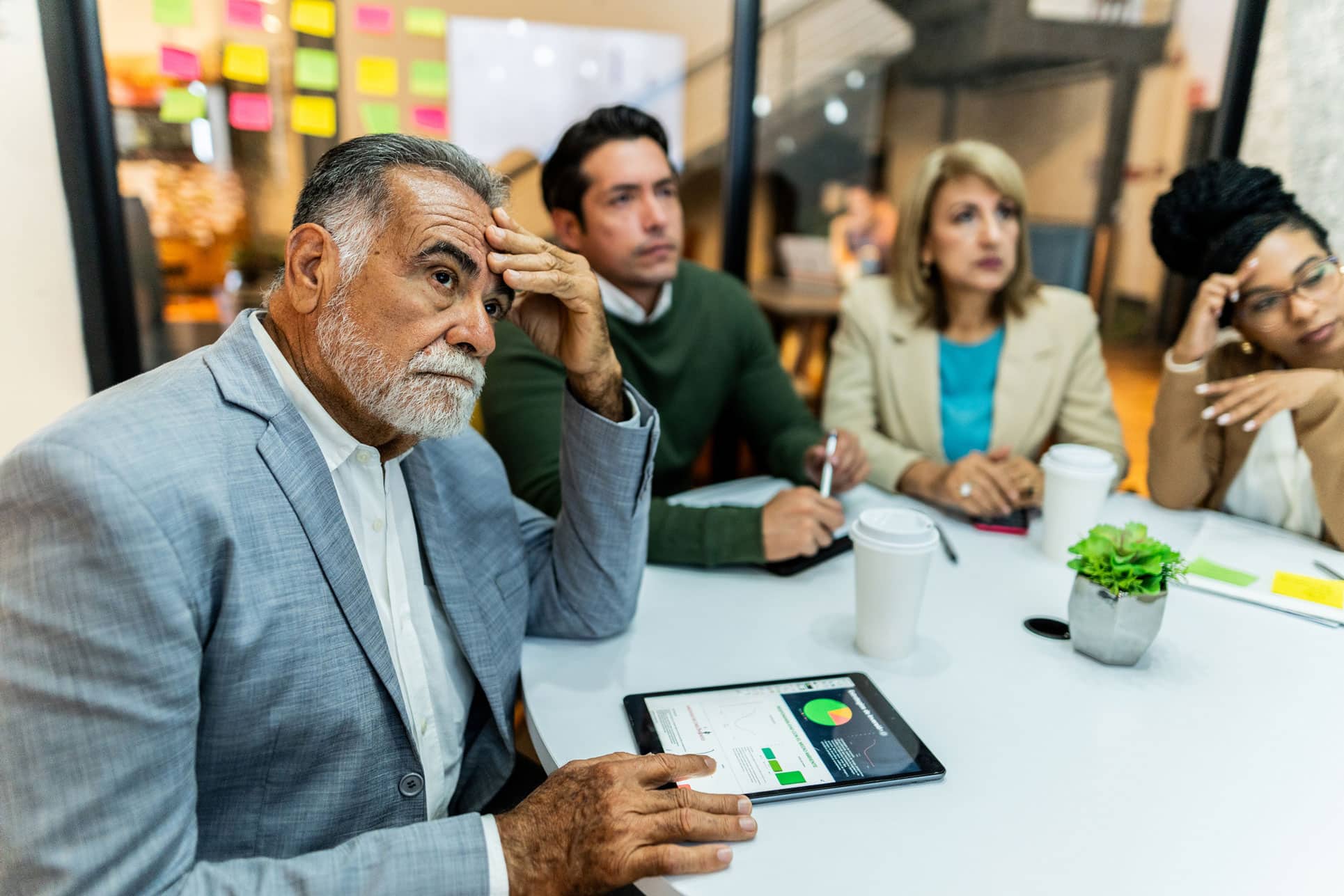Four professionals at a Business Valuation Consulting Firm look concerned during a meeting.