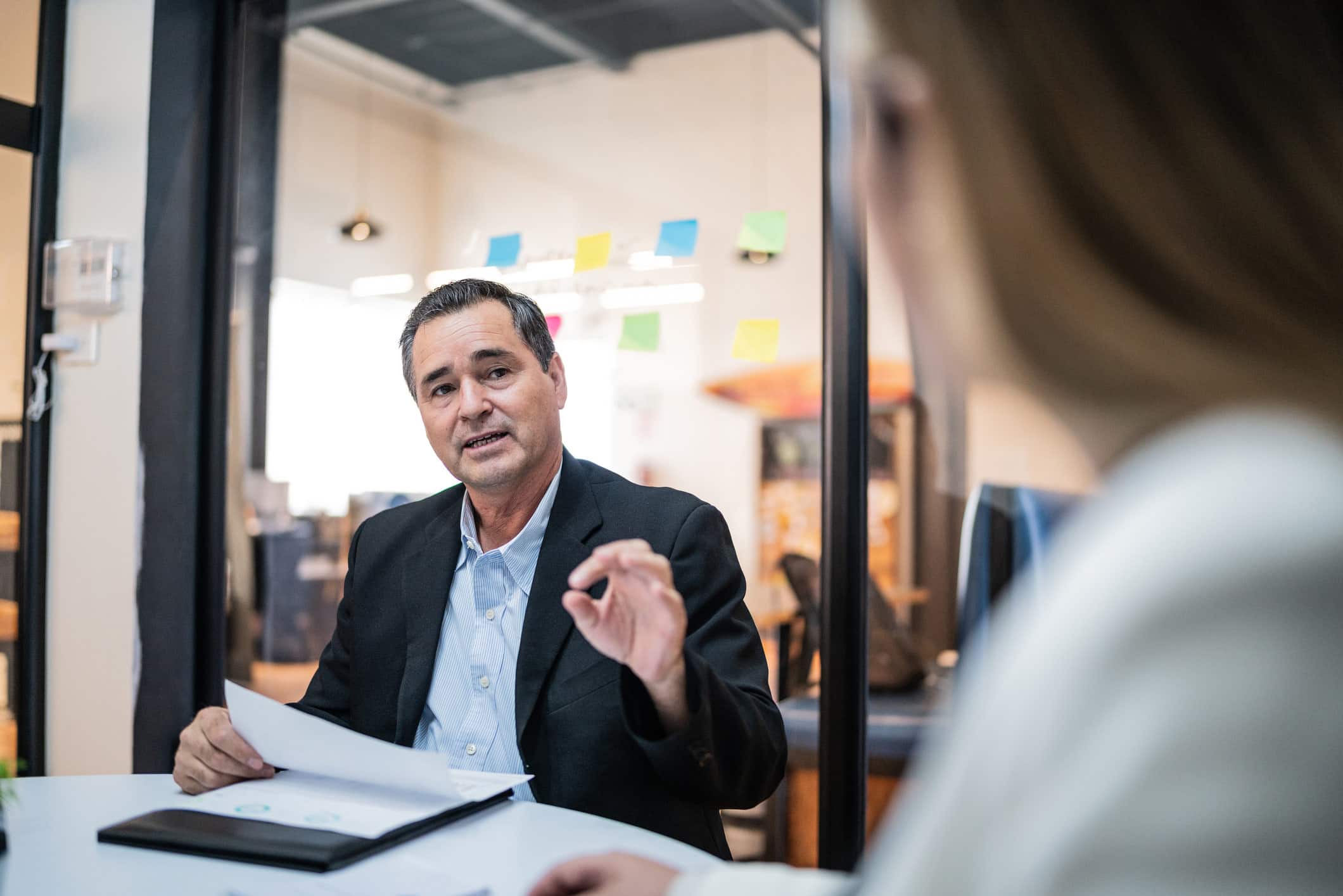 Man in suit discusses NLP for Legal Documents with woman in an office meeting room.