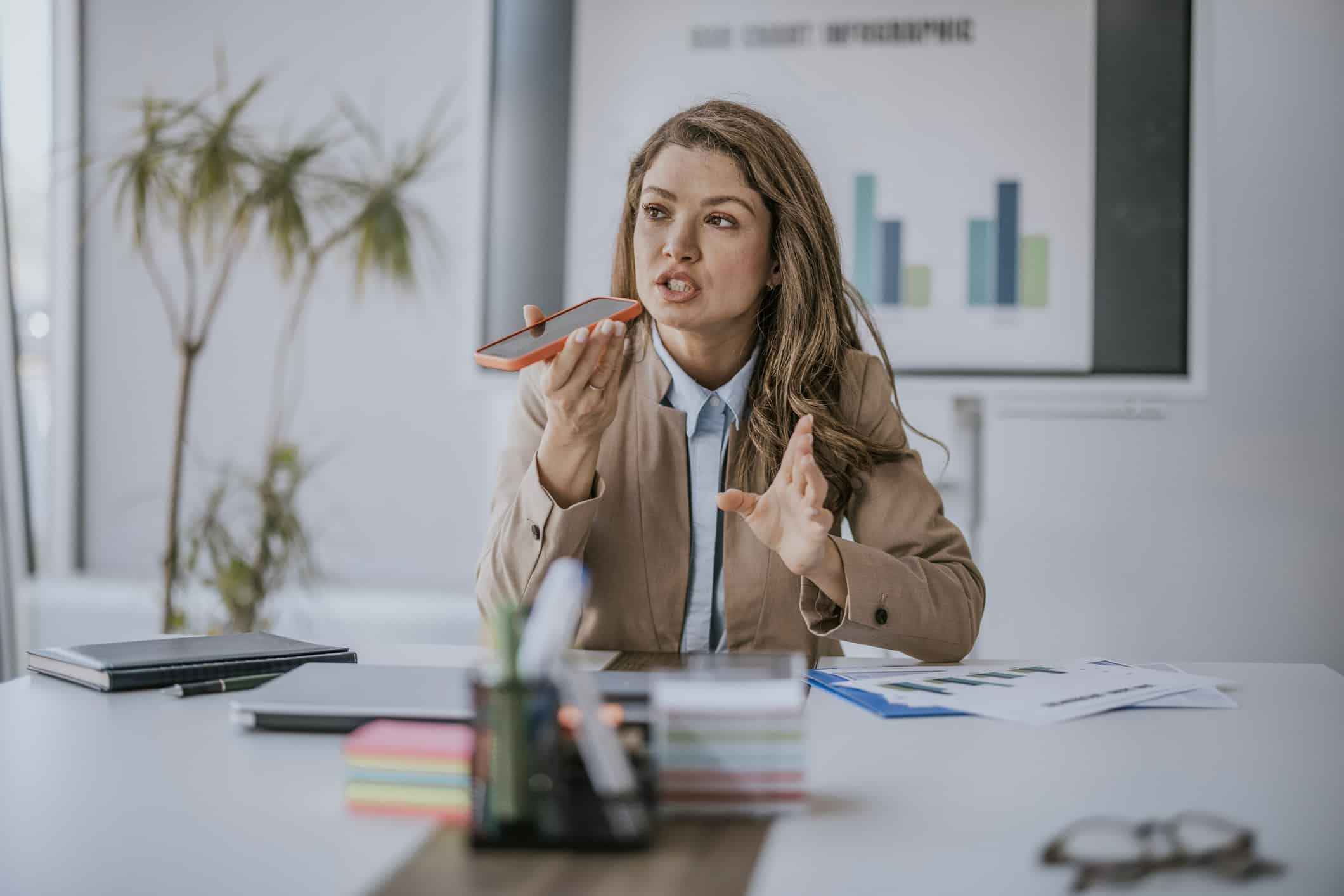 Woman in a suit discussing law firm operations consulting at her desk with charts behind her.