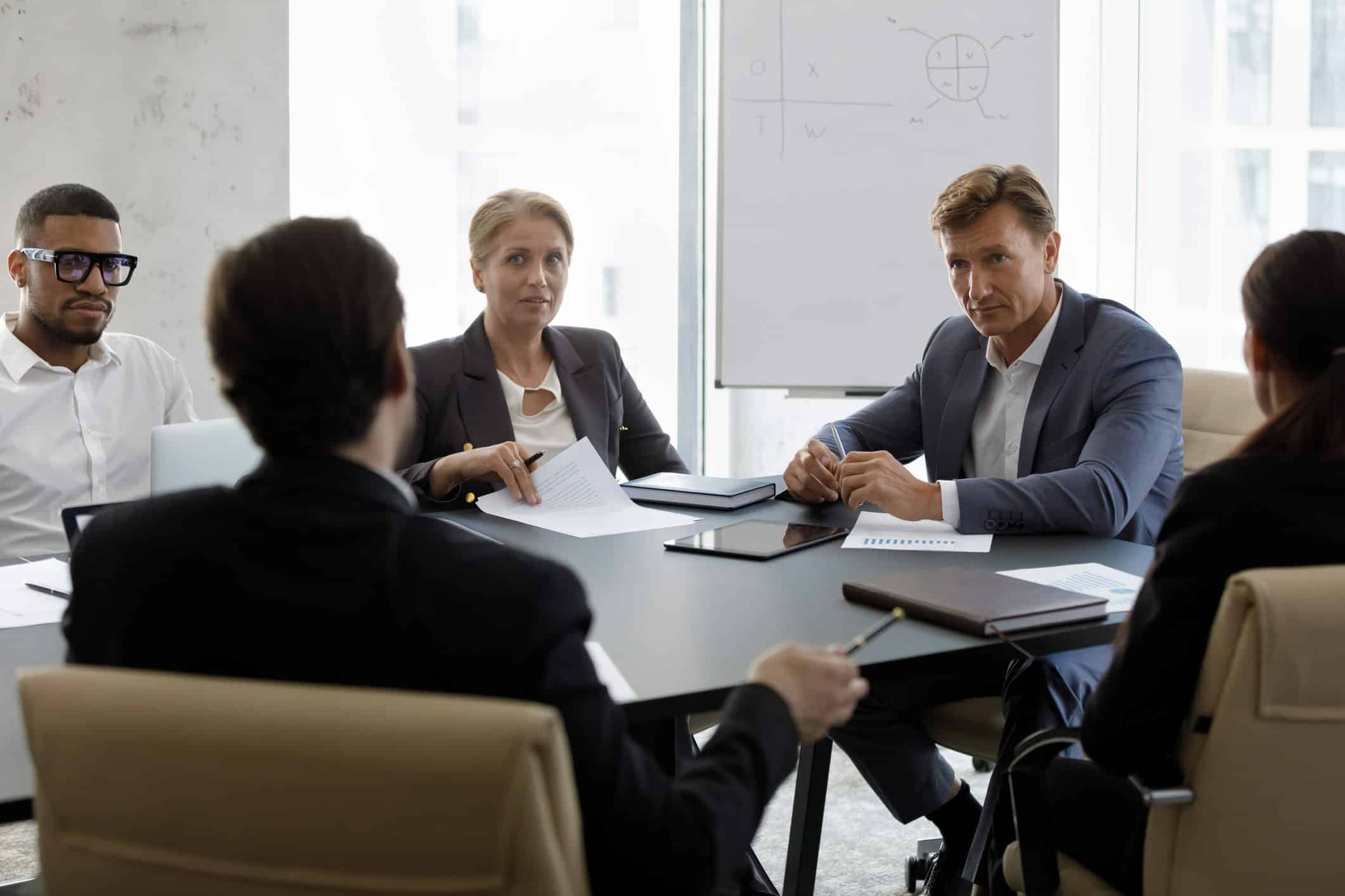 Four people in business attire discuss workforce development consulting around a conference table.
