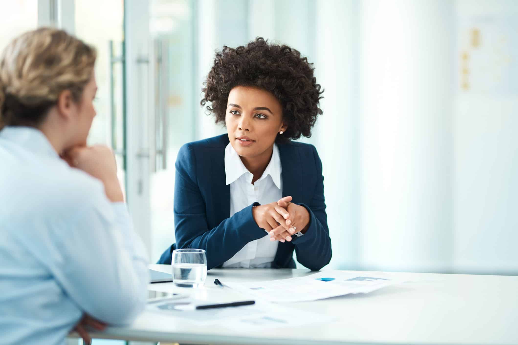 Two women discuss Strategic Law Firm Financial Benchmarking in a bright, modern office.