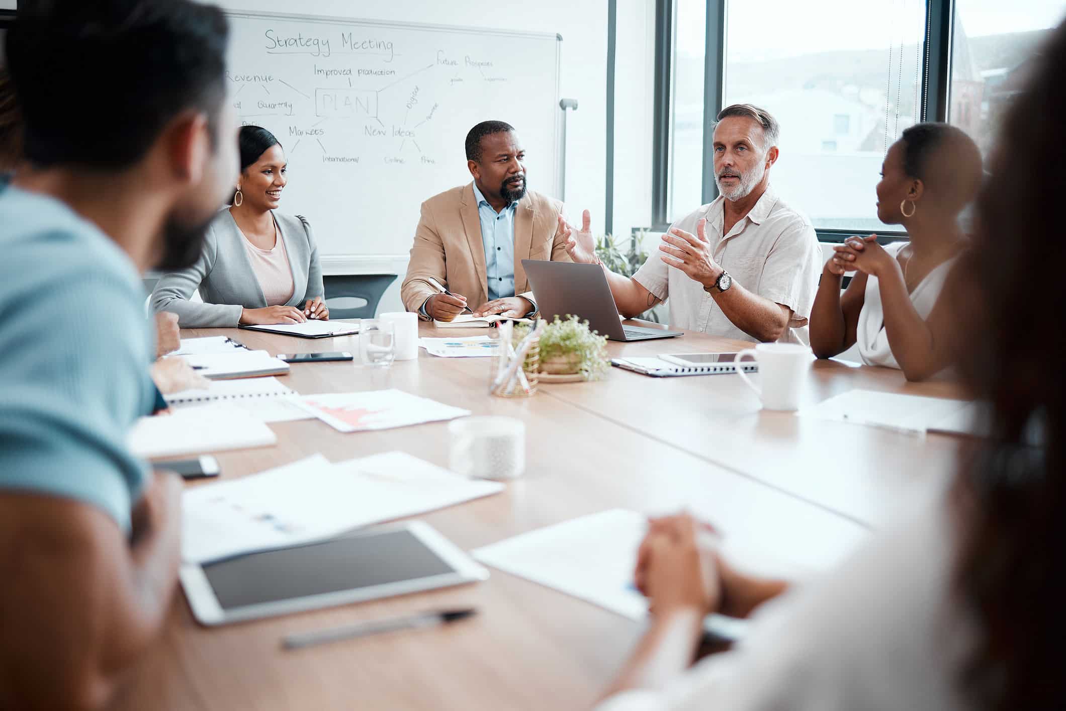 Six people discuss change management planning around a conference table in a modern office.