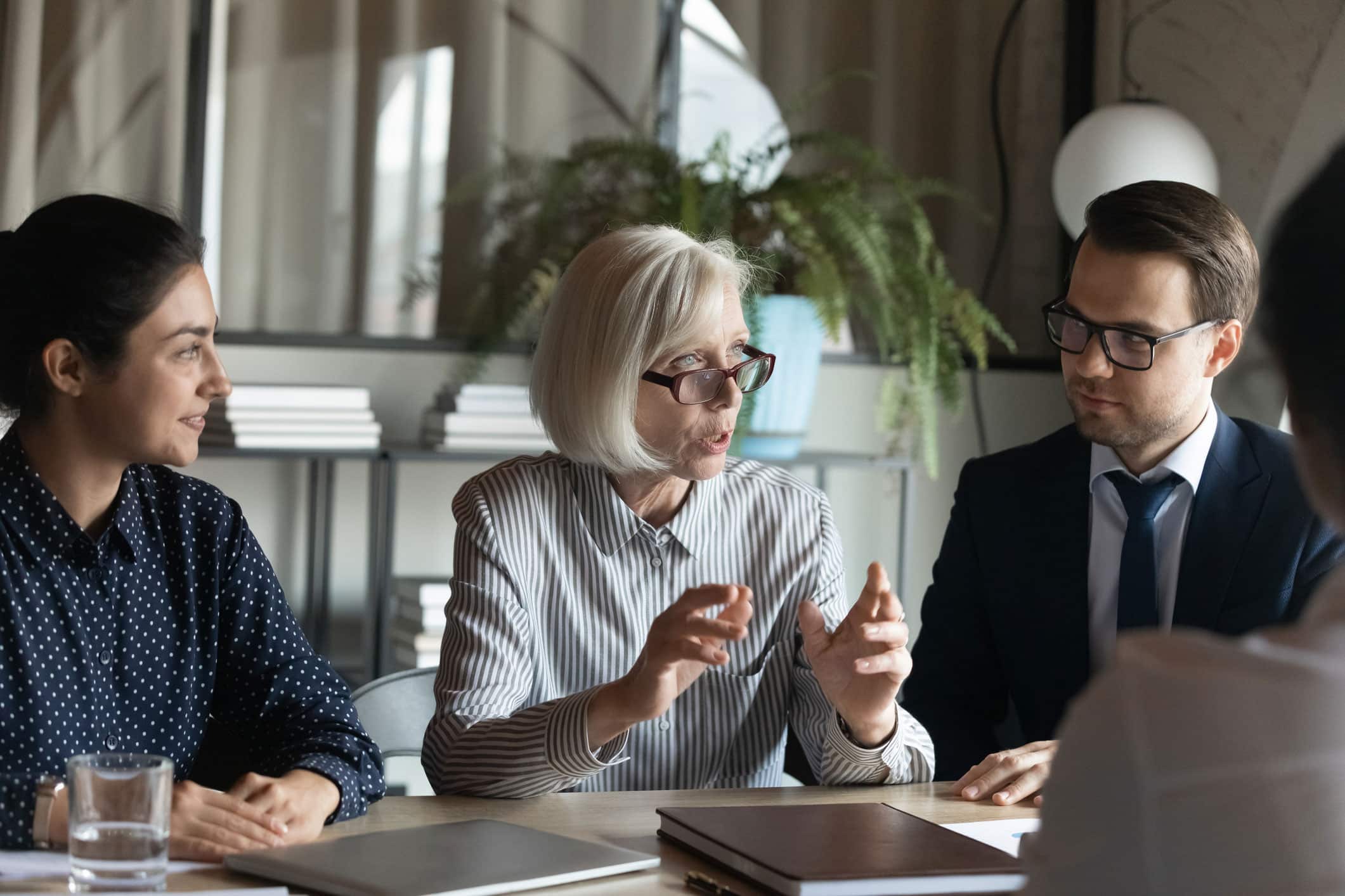 Three people in a meeting discuss Business Intelligence Execution around a table with documents.