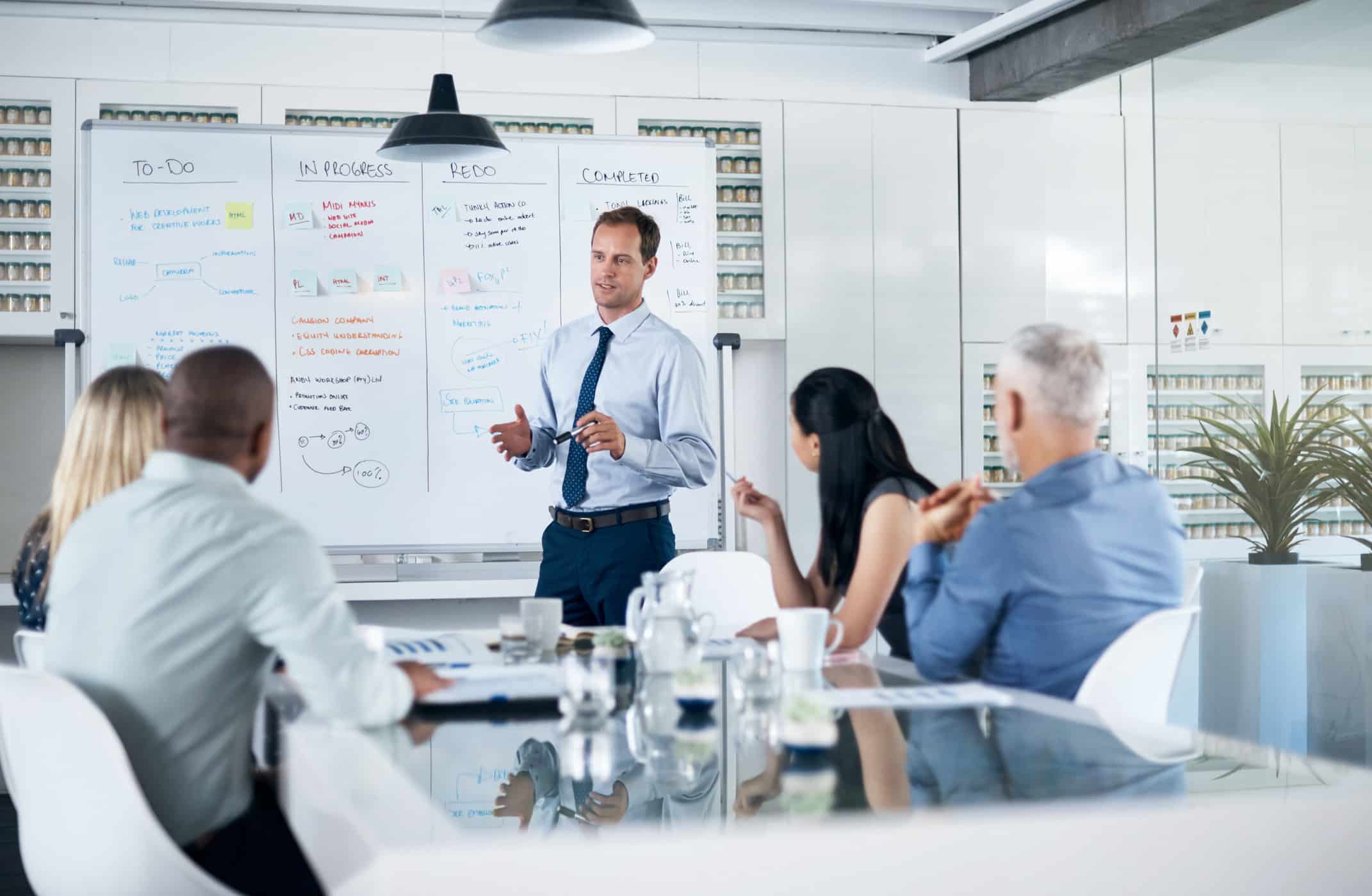 Businessman presents Modern Data Architecture Execution ideas to colleagues in a office setting.