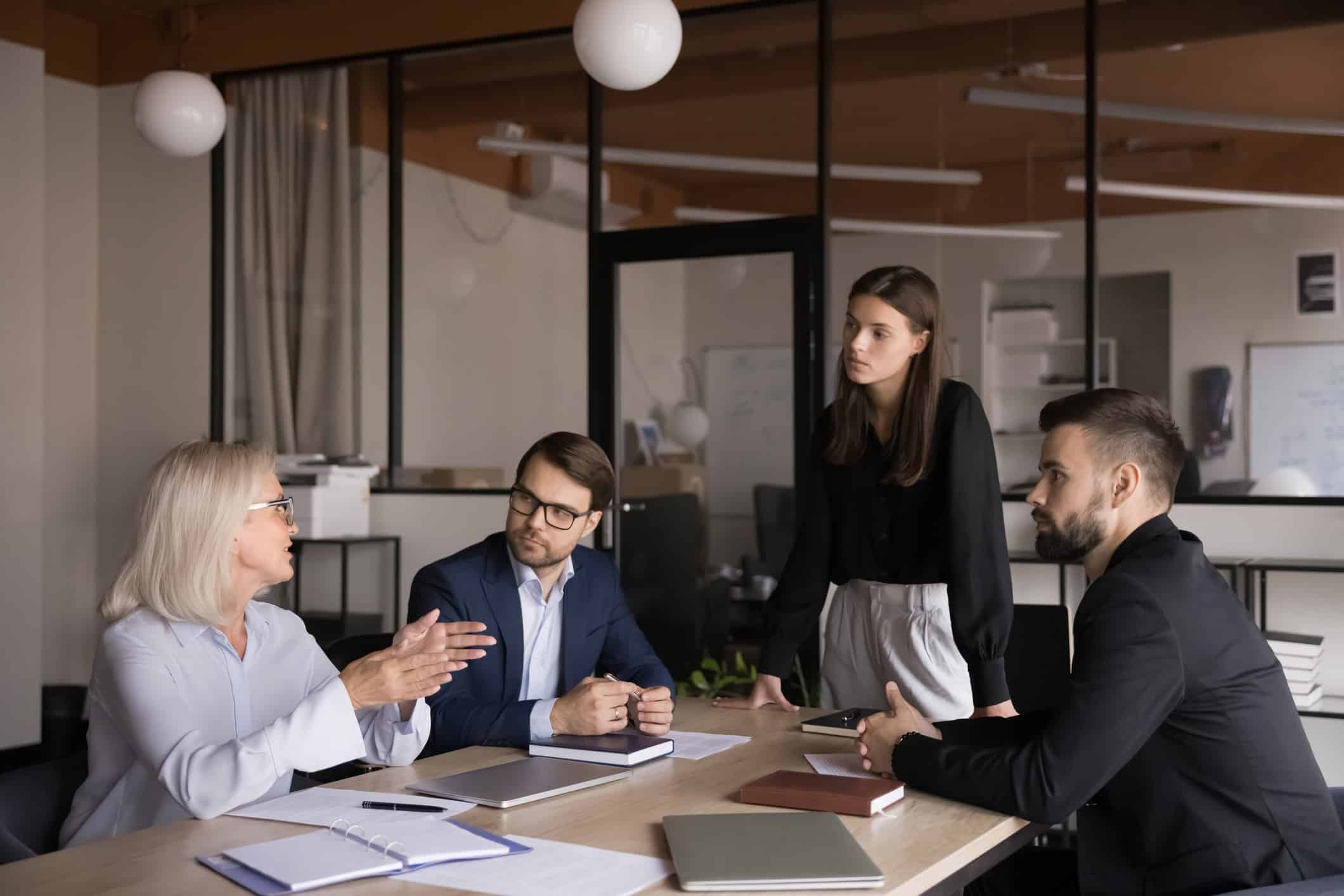 Four people discuss statistical modeling and strategy in a modern office setting.