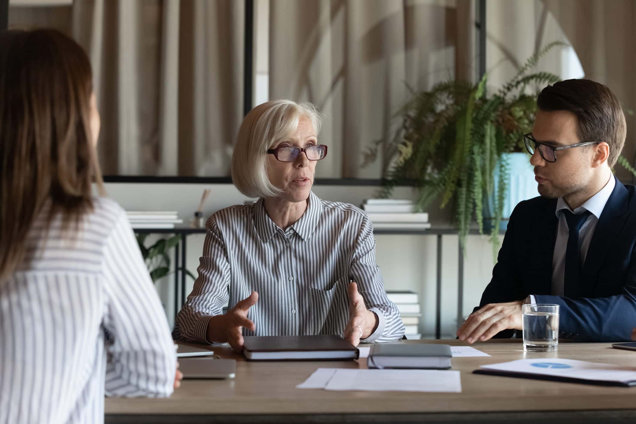 Three people discuss M&A Integration Planning at a table in an office setting.