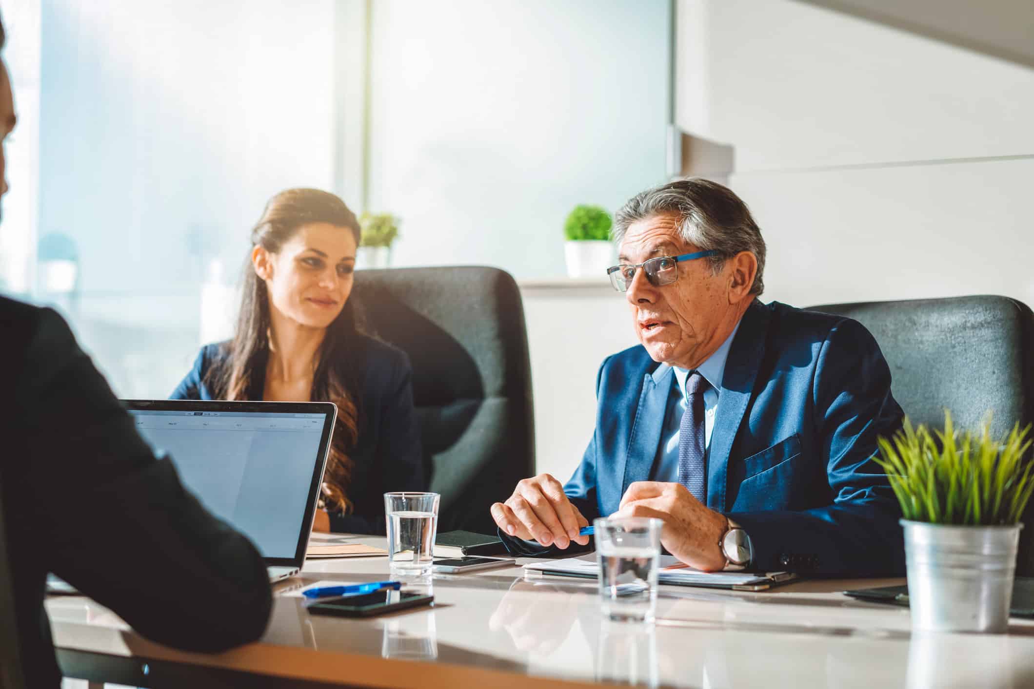 Three people discussing data governance at a conference table in a modern office.