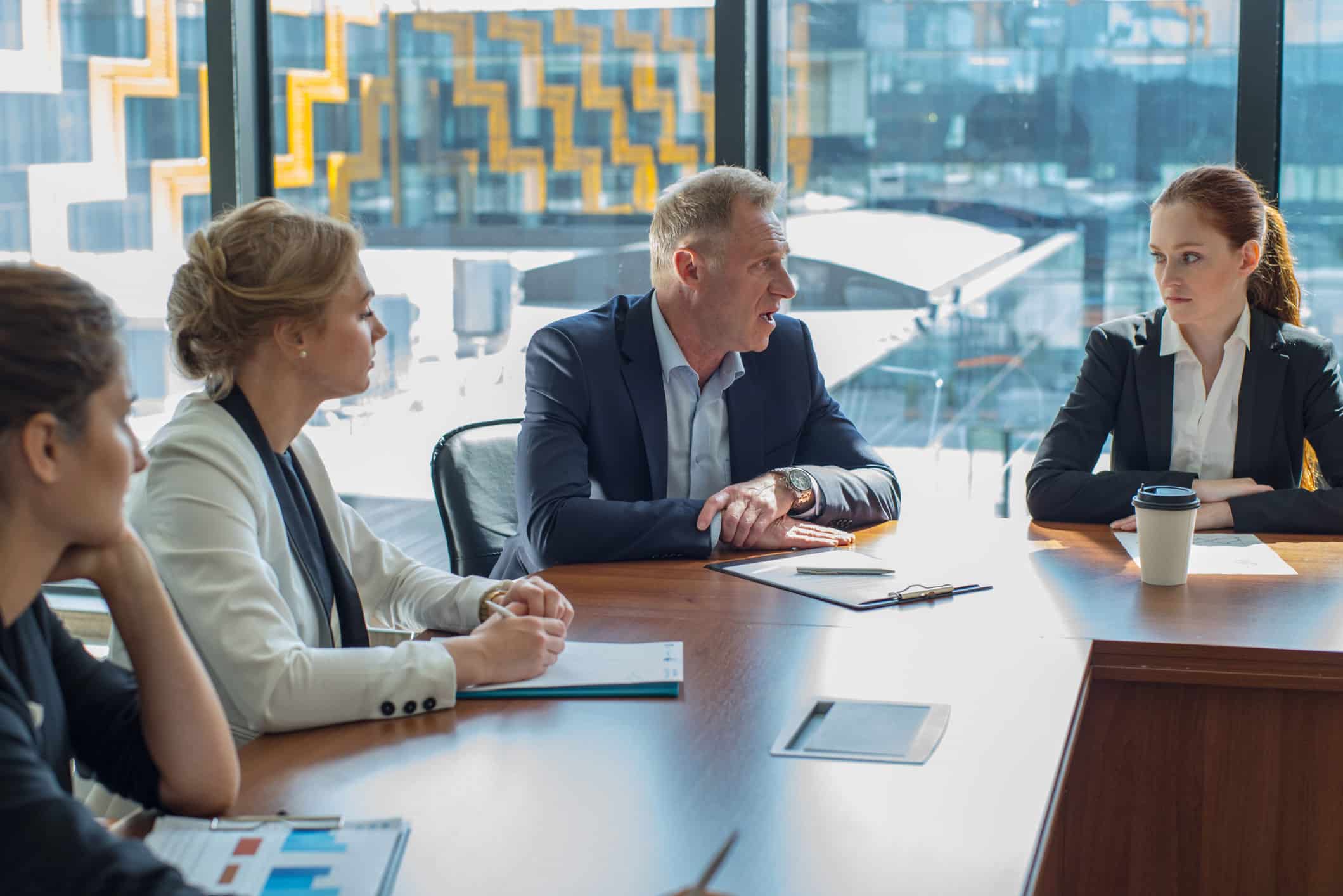 Four business people discuss employee wellness integration at a modern conference table.
