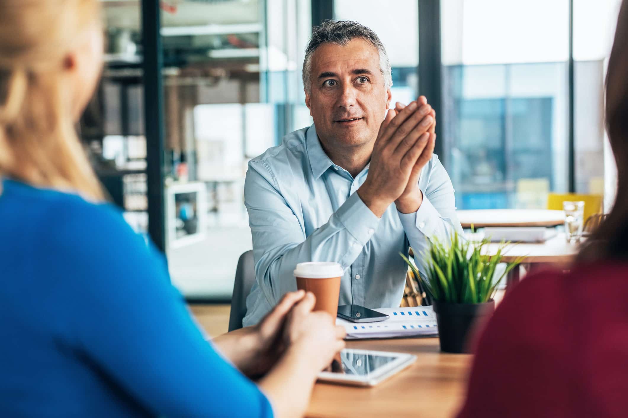 Man in meeting, discussing organizational strategy planning with two colleagues in a modern office.