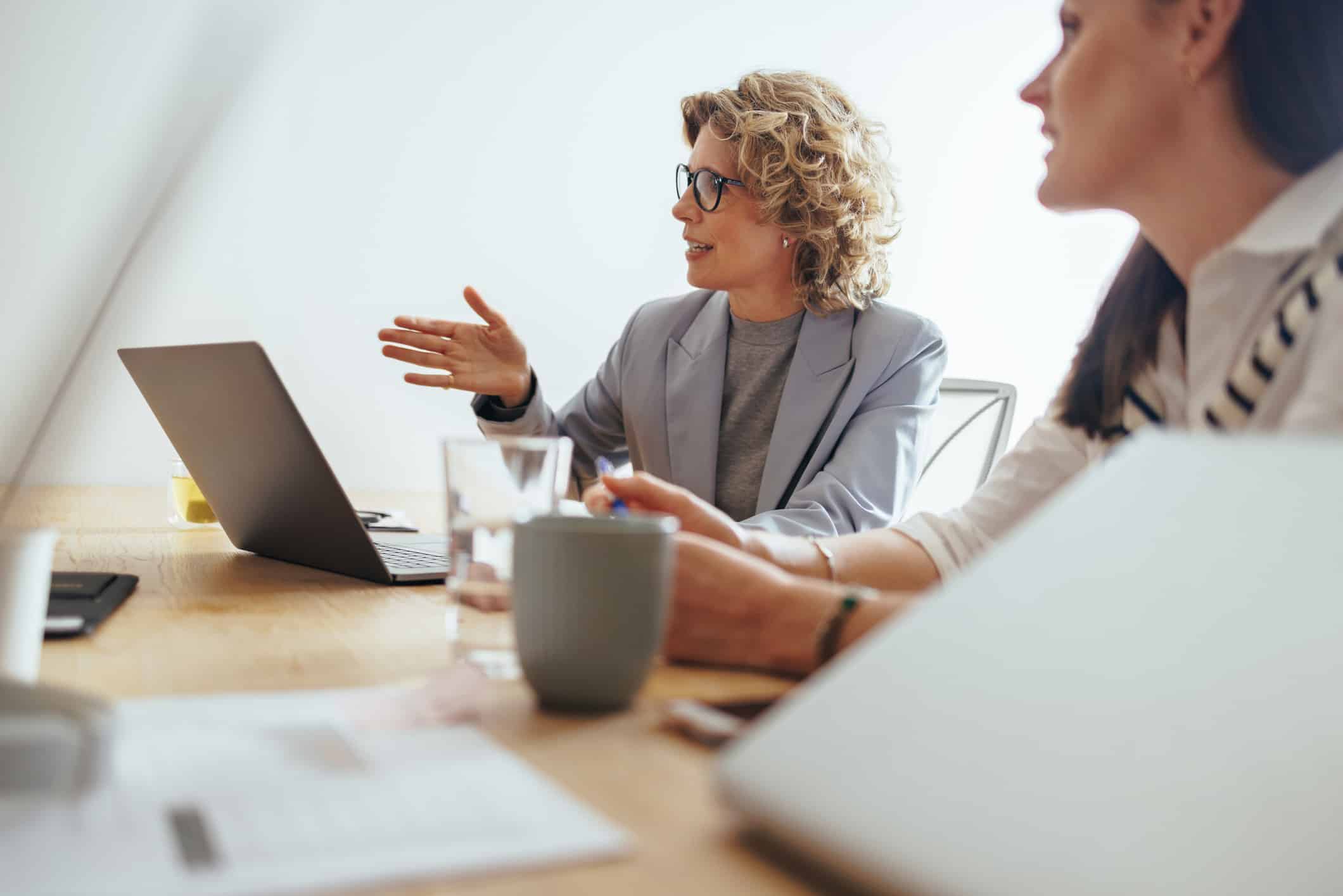 Two women discuss eDiscovery document review process planning at a desk with laptops and coffee.