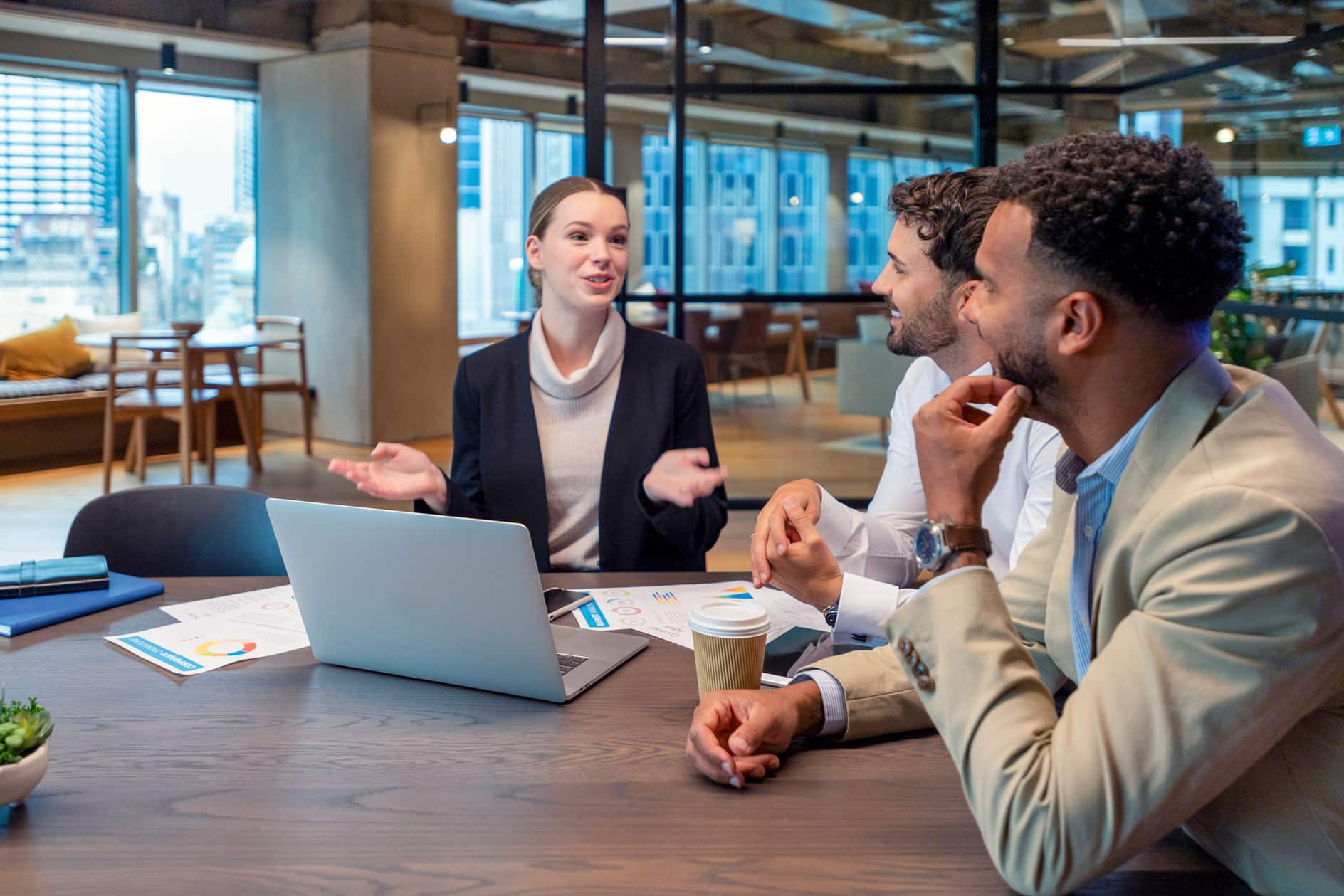 Three colleagues discuss Data Governance Alignment at a table with a laptop in a modern office.