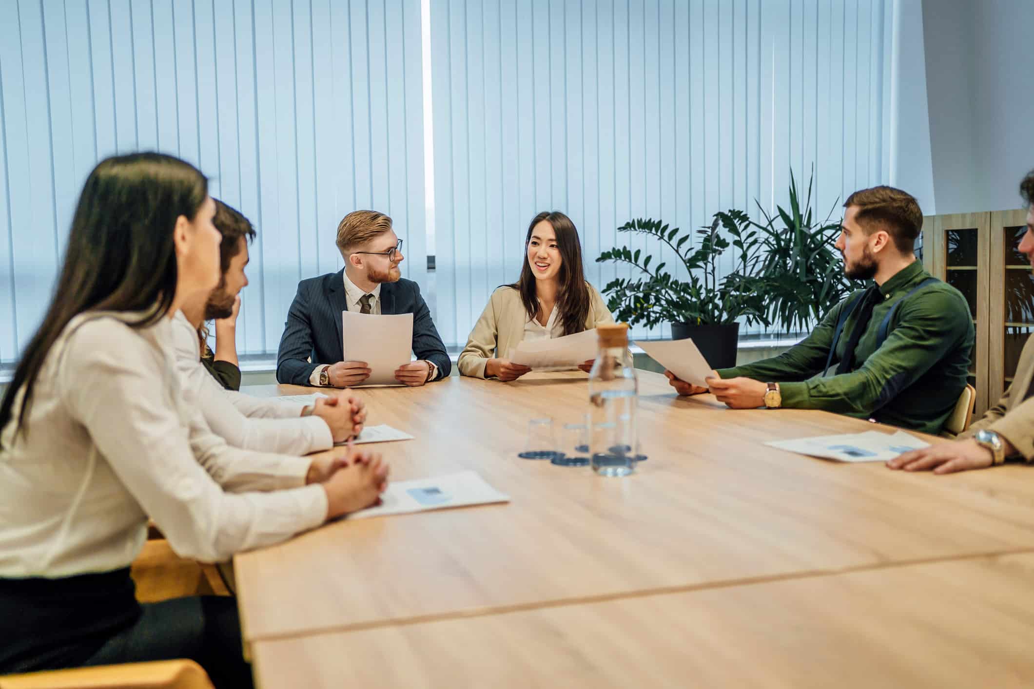 Six people in business attire discuss Business Intelligence Alignment around a conference table.