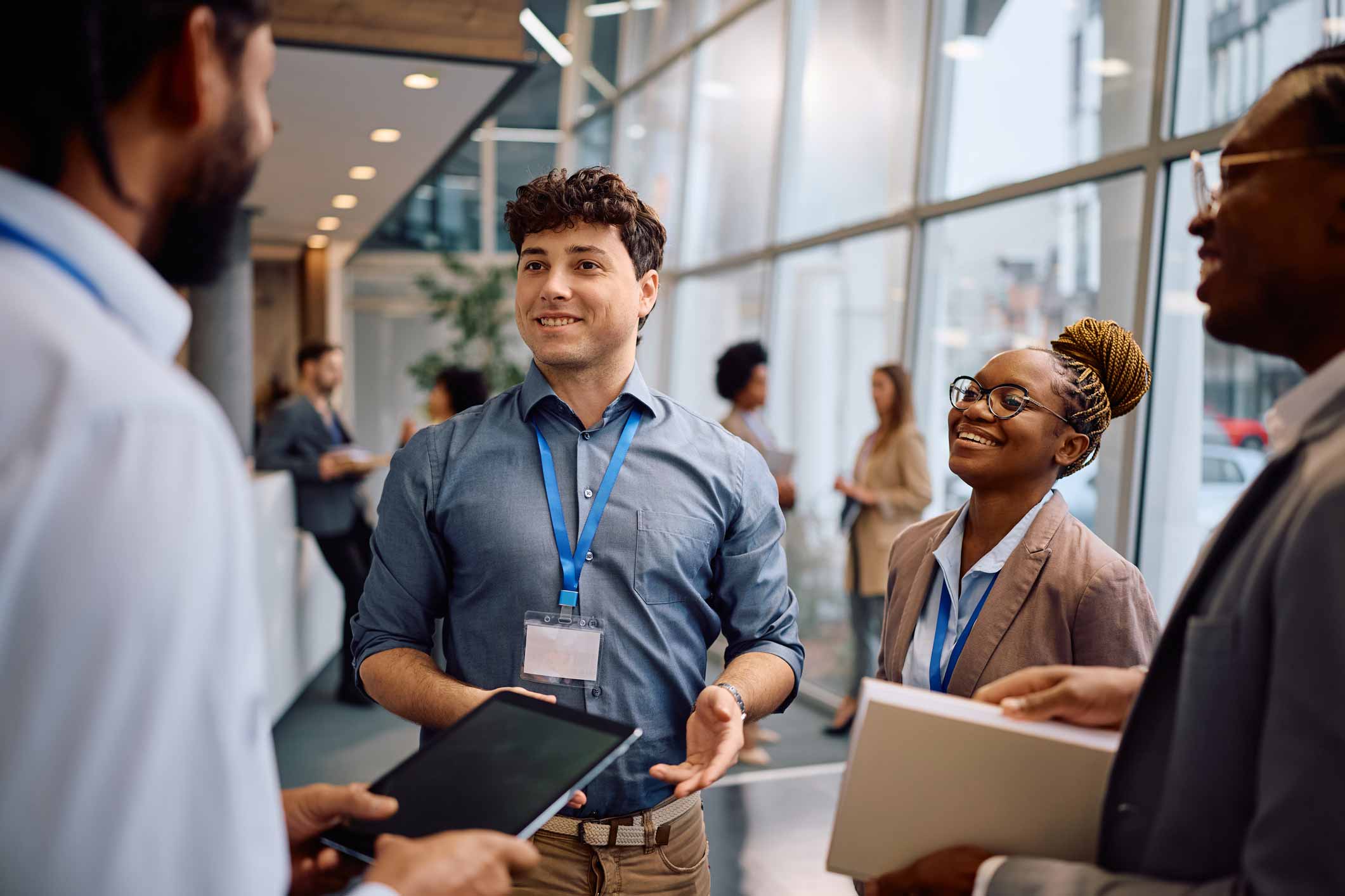 Four professionals discussing MDM Talent Alignment, smiling in a modern office hallway.