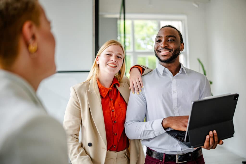 Two colleagues smiling, discussing employee wellness alignment with a third person in the office.