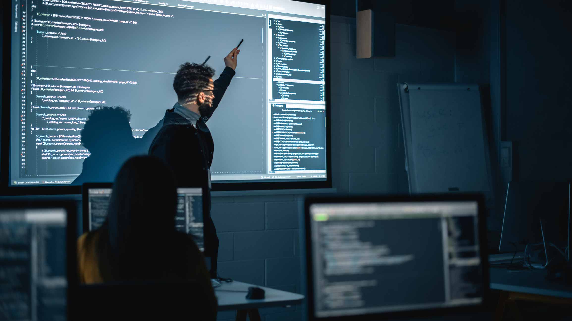 Person presenting code on Cybersecurity Talent Alignment to a group in a computer-filled classroom.