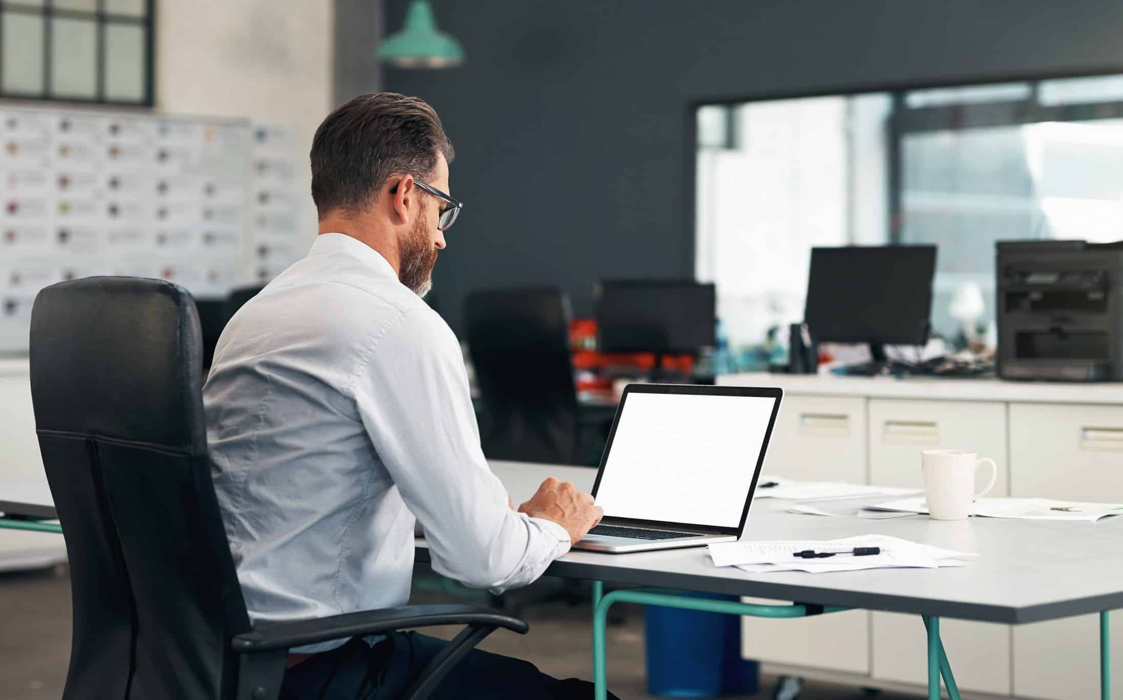 Man with glasses working on Big Data Strategy Enablement at a laptop in a modern office.