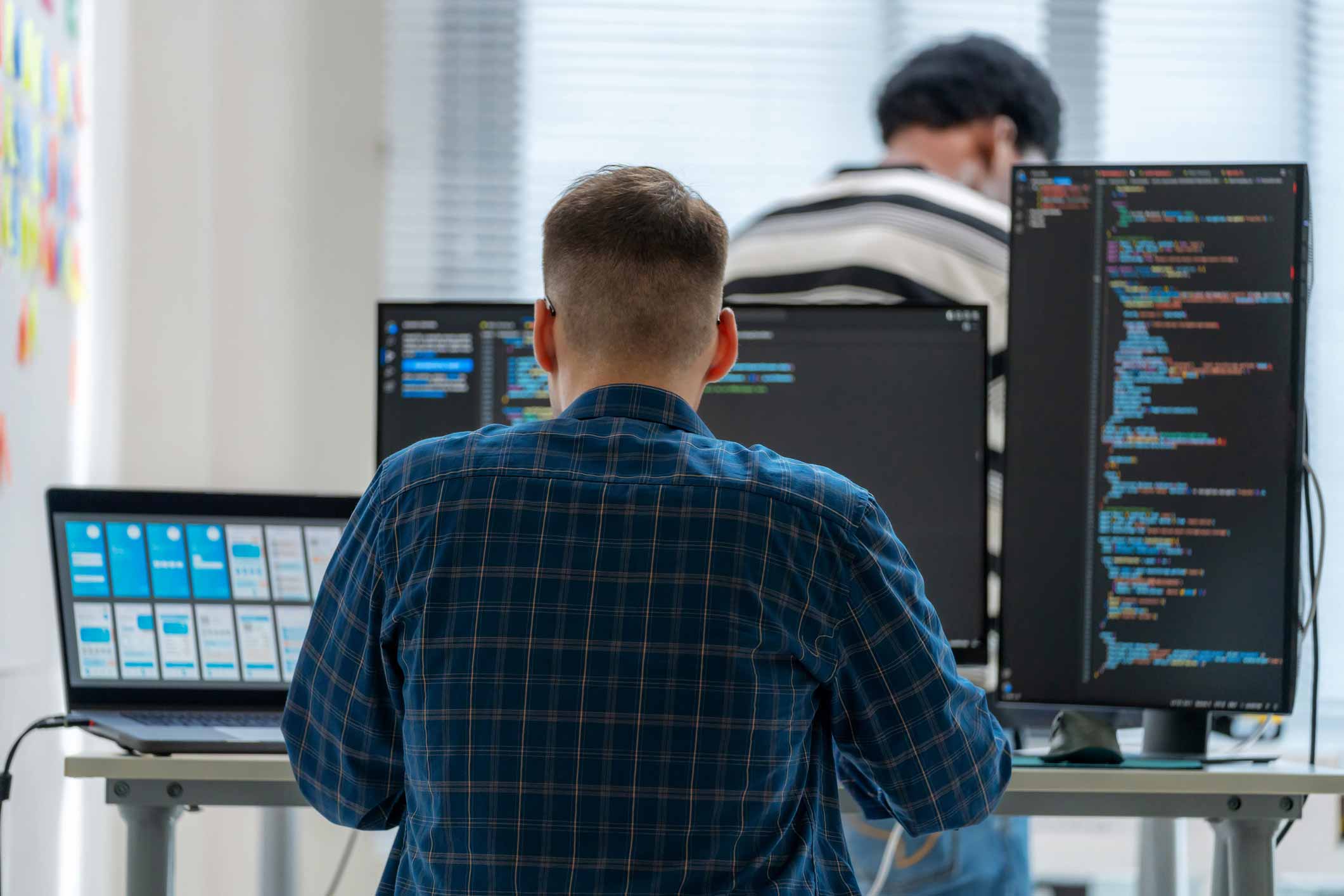 Person working at a desk with multiple screens displaying code and MDM Technology Enablement.