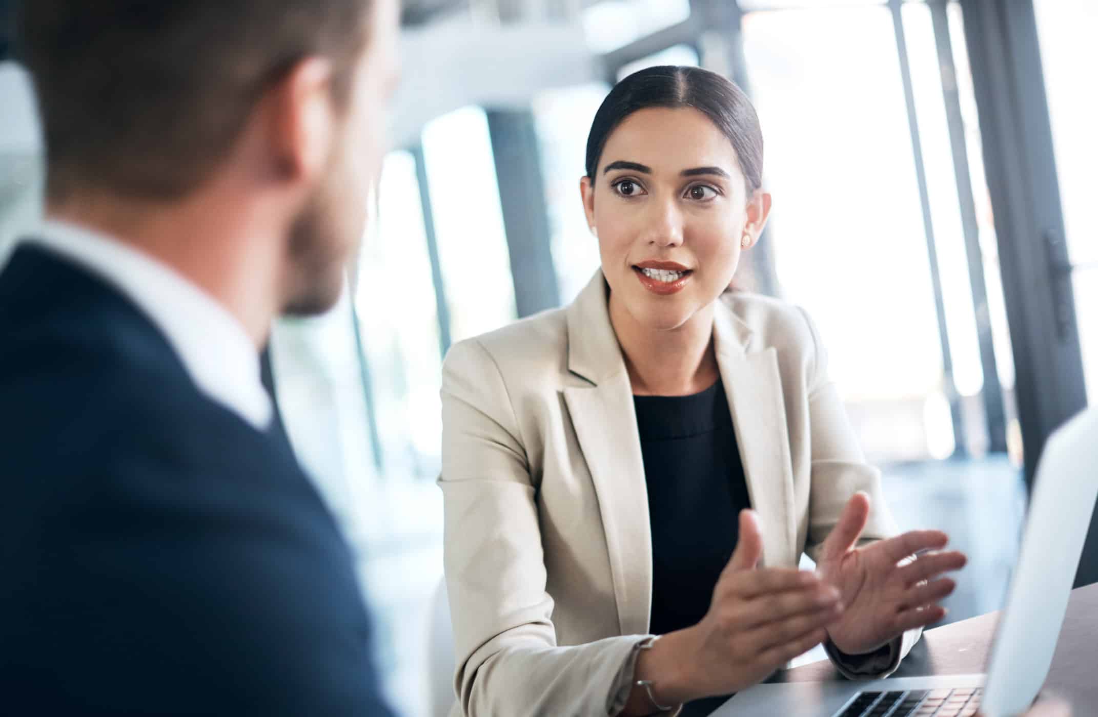 Woman in business attire discusses Data Governance Enablement with a colleague in the office.