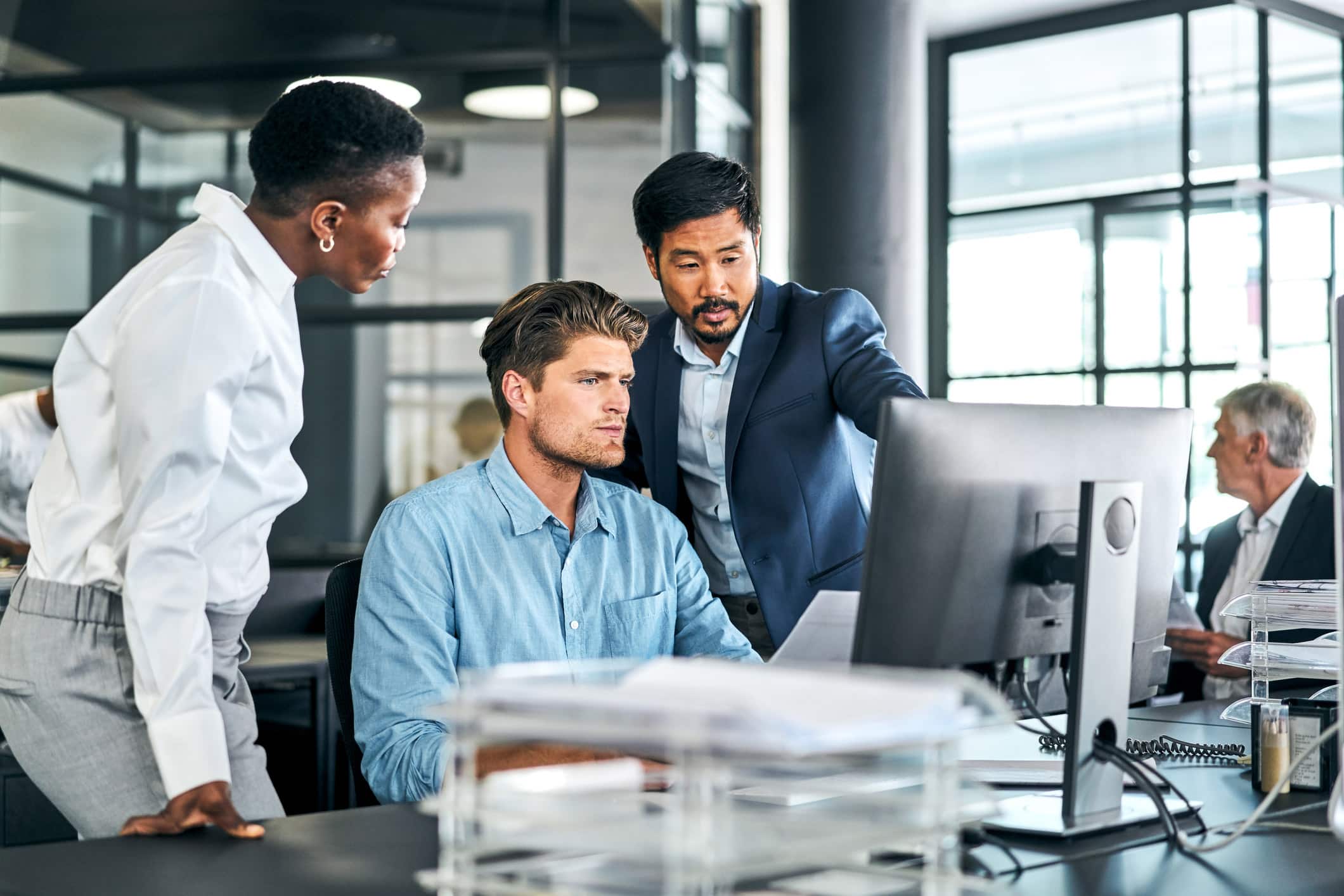 Three colleagues discuss BPM technology integration at a law firm in a modern office.