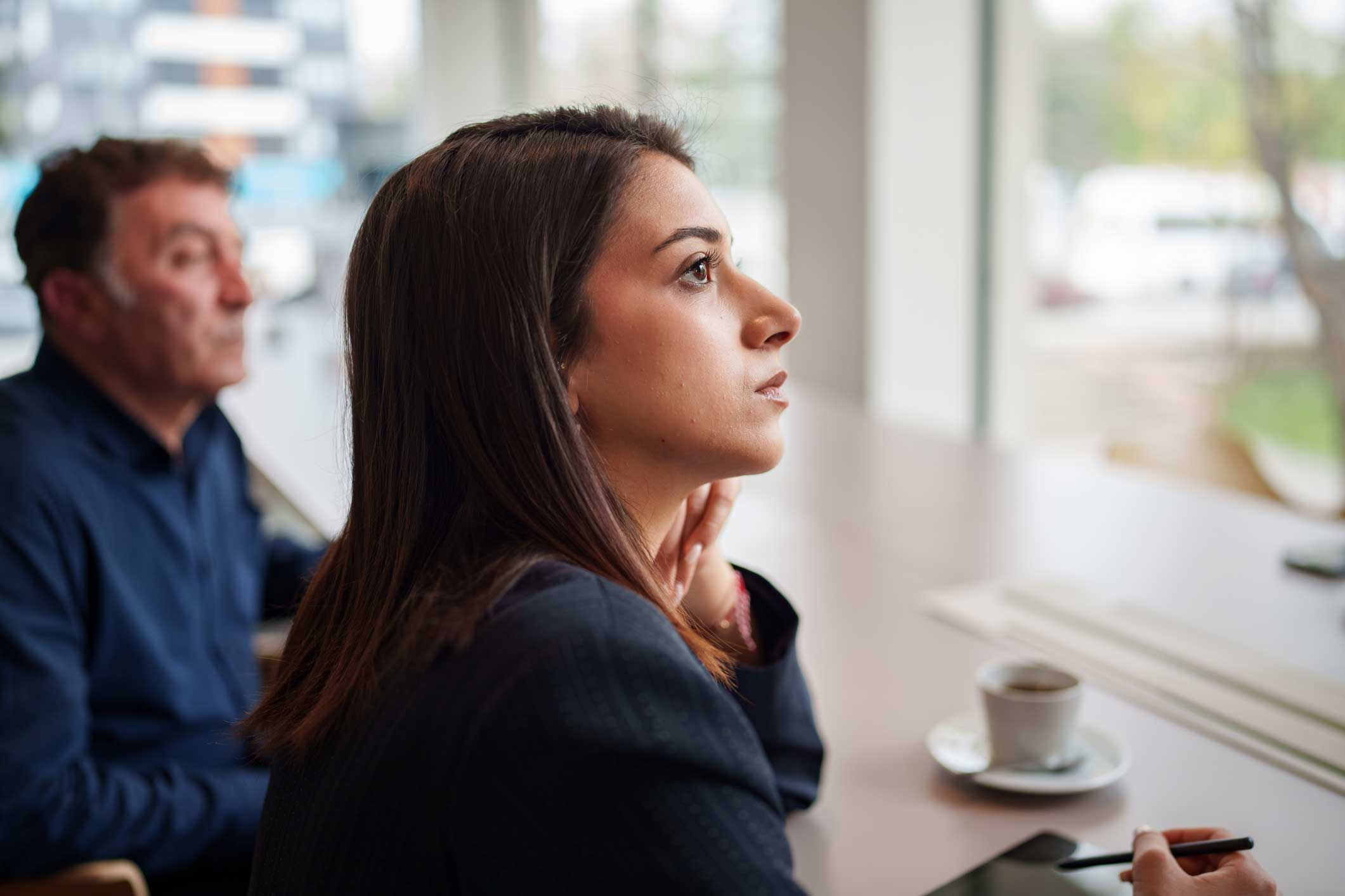 Woman in business attire at a Cybersecurity Consulting Firm meeting, listening attentively.