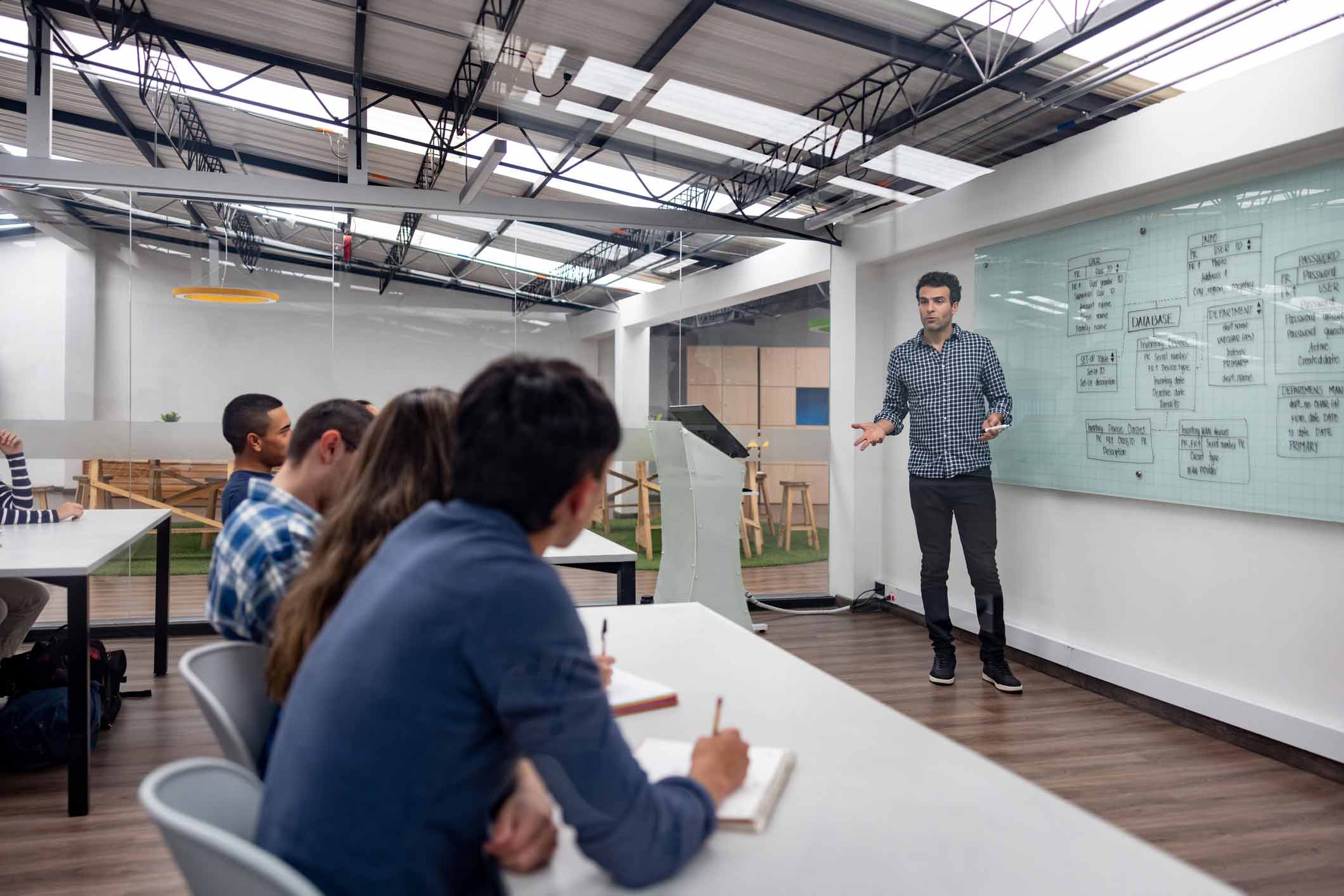 Man giving a presentation to students in a classroom with a whiteboard.