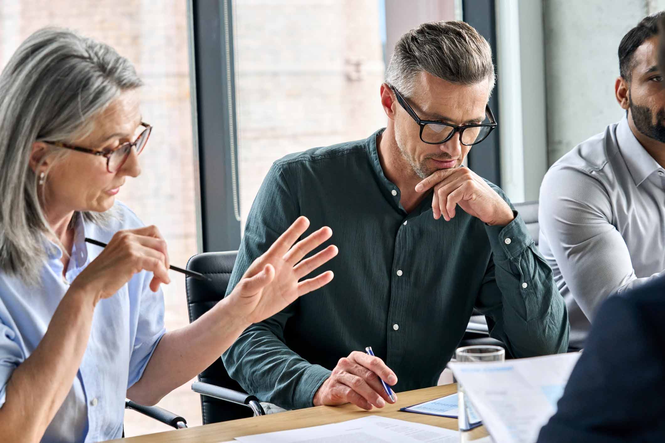 Three people discuss Machine Learning Consulting Services in a modern office setting.