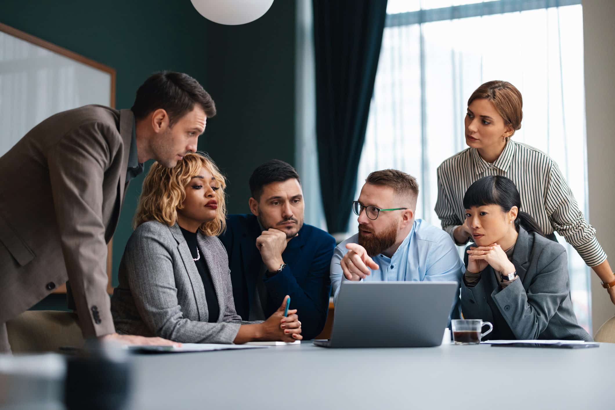 Six business people discuss Healthcare Litigation Support consulting services around a laptop.