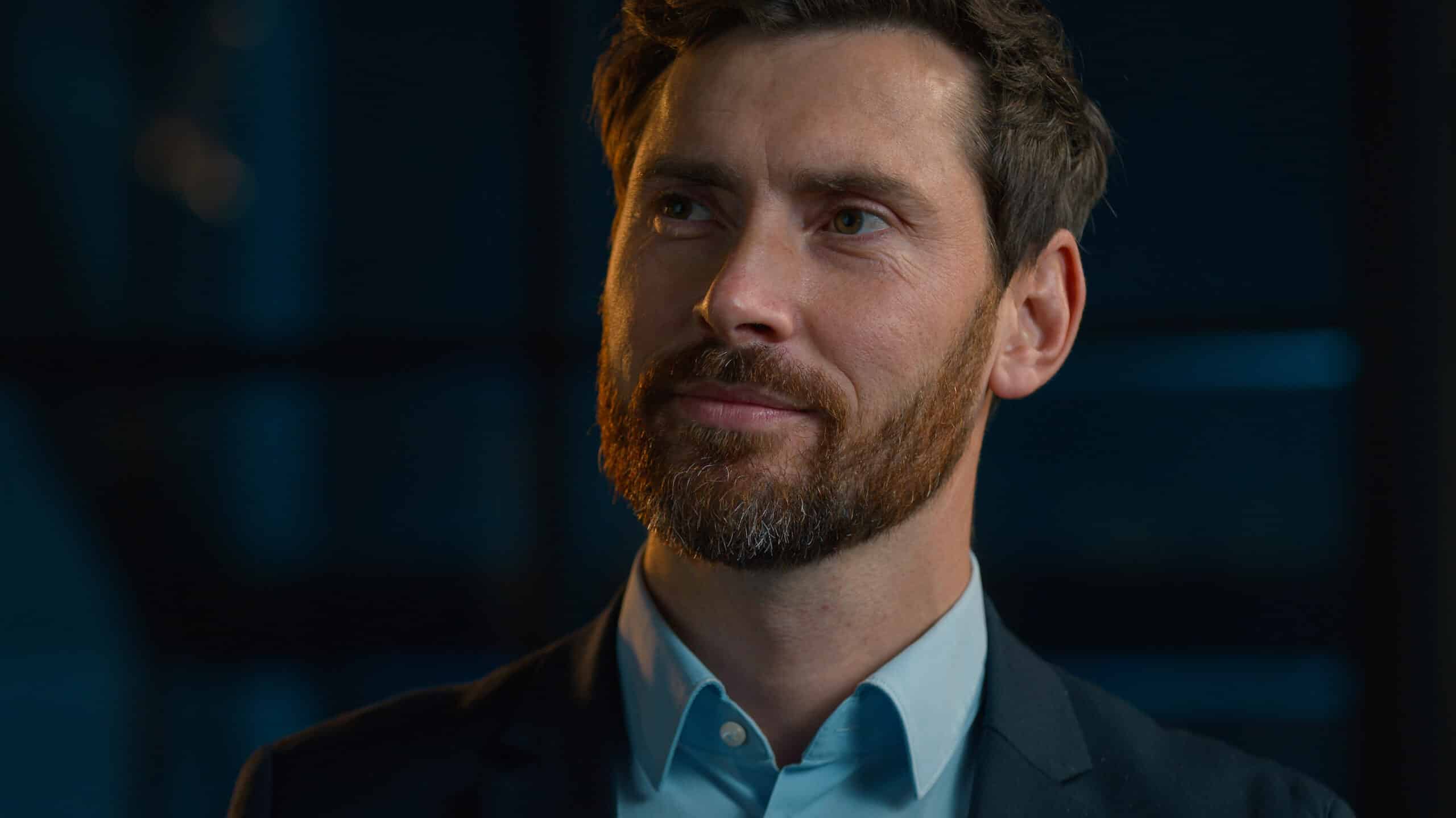 Man with brown hair and beard in suit, symbolizing expertise in Expense Reduction Consulting.