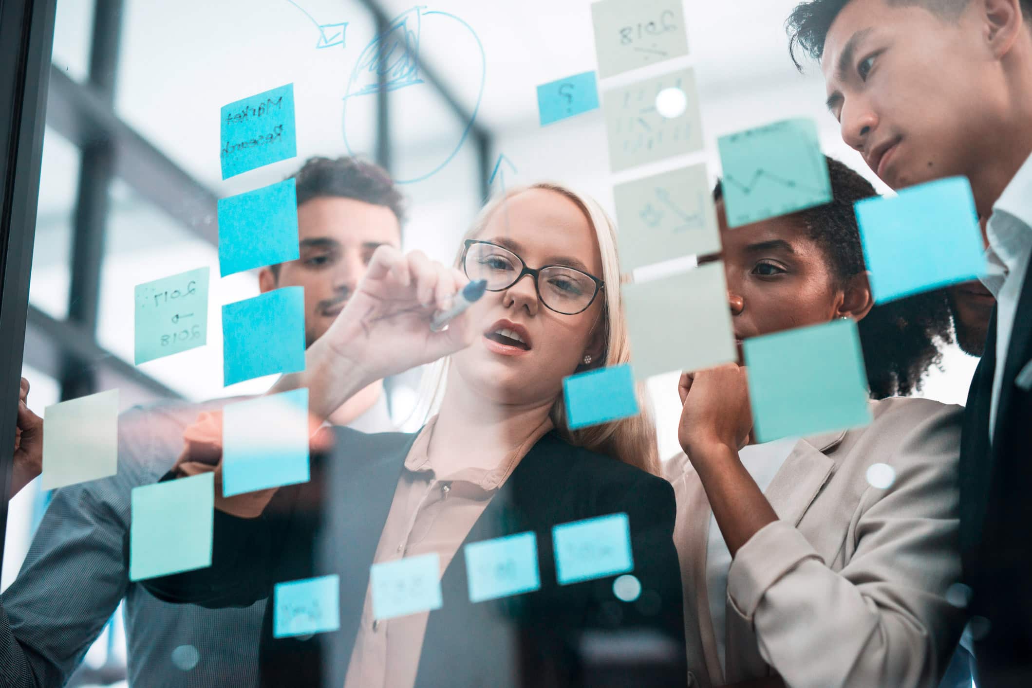 Four people brainstorm Law Firm Marketing Consulting ideas on sticky notes during a meeting.