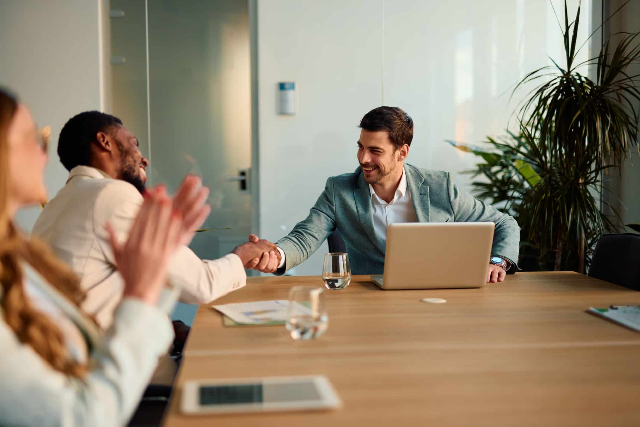 Two men shaking hands at a meeting table, celebrating Vendor Oversight & Budget Control success.