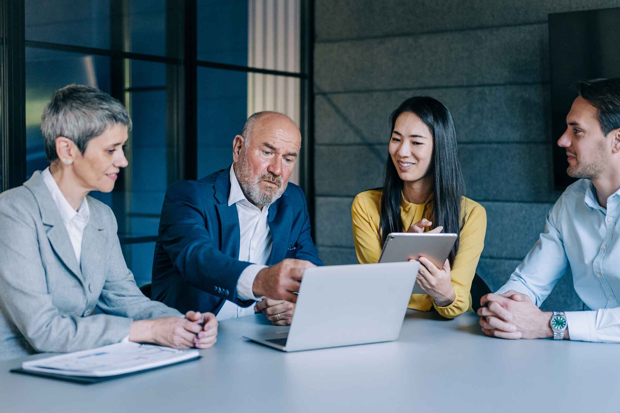 Four professionals discuss Cybersecurity Advisory around a laptop in a modern office.