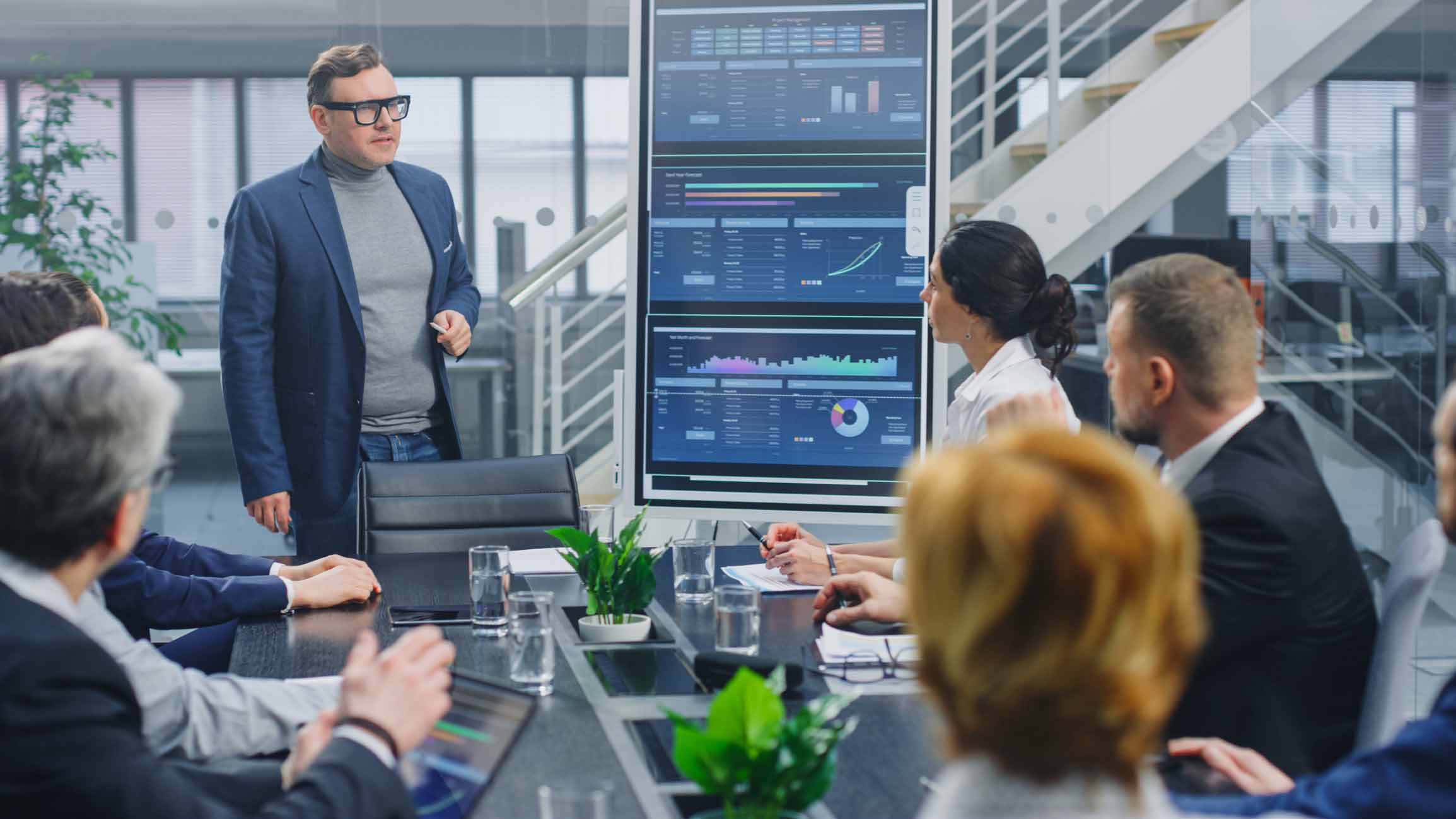Man presenting advanced analytics consulting data to colleagues in a modern conference room.