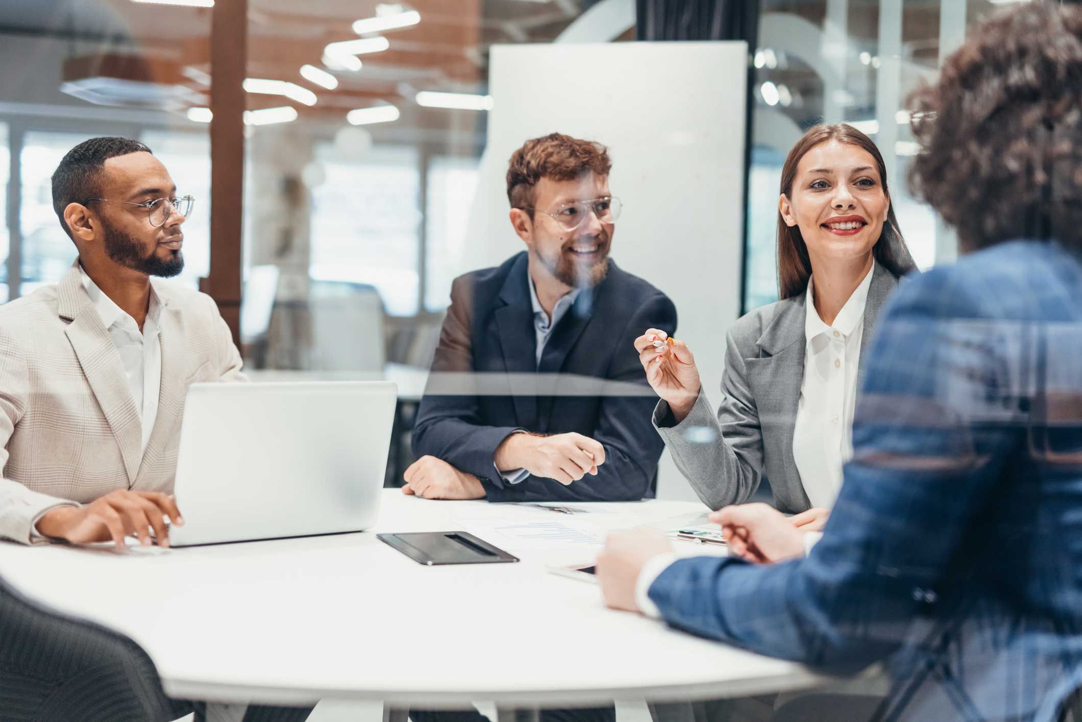 Four business professionals discuss Legal Automation Consulting in a modern office.