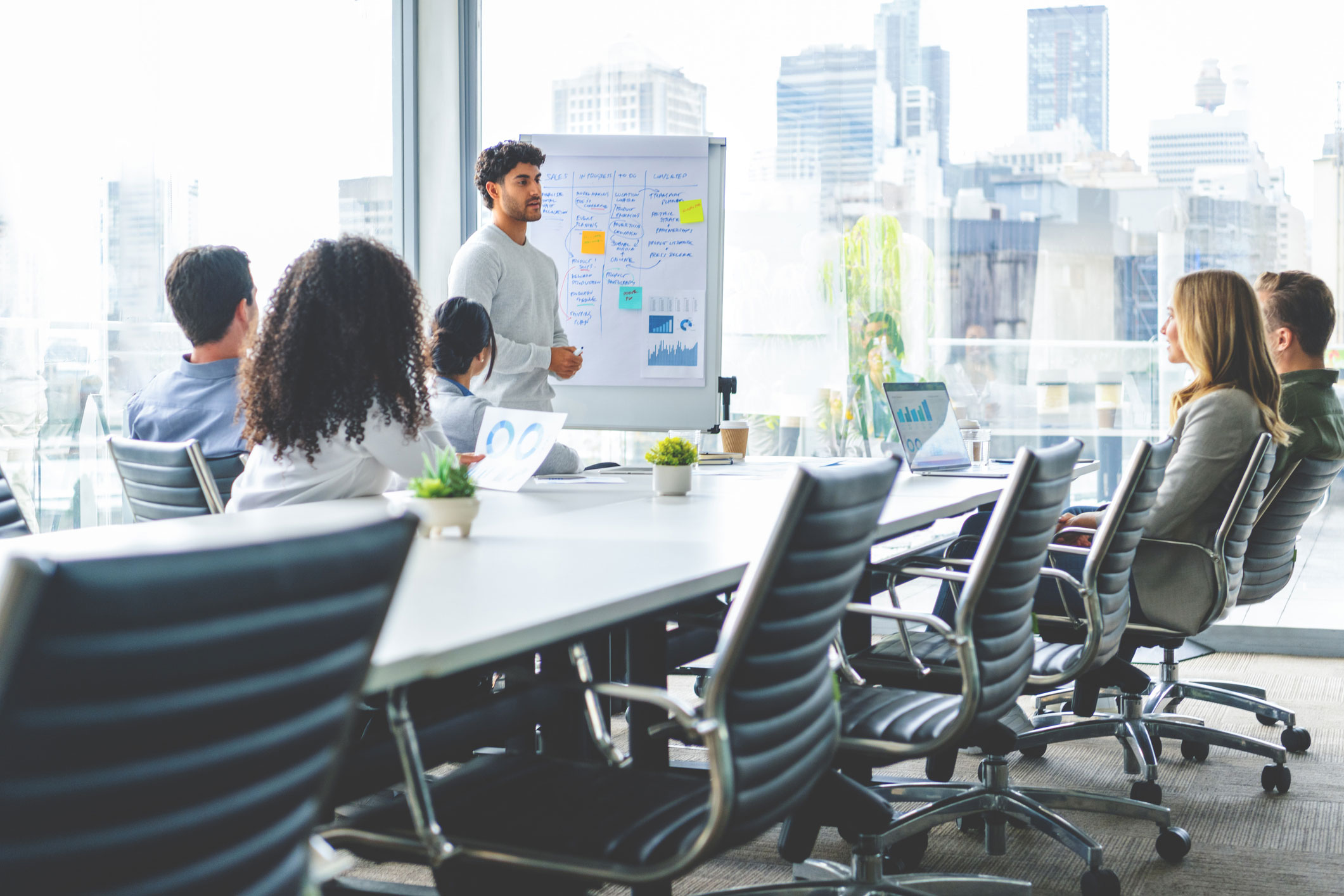 Man presenting law firm strategic planning to colleagues in a modern office with city view.