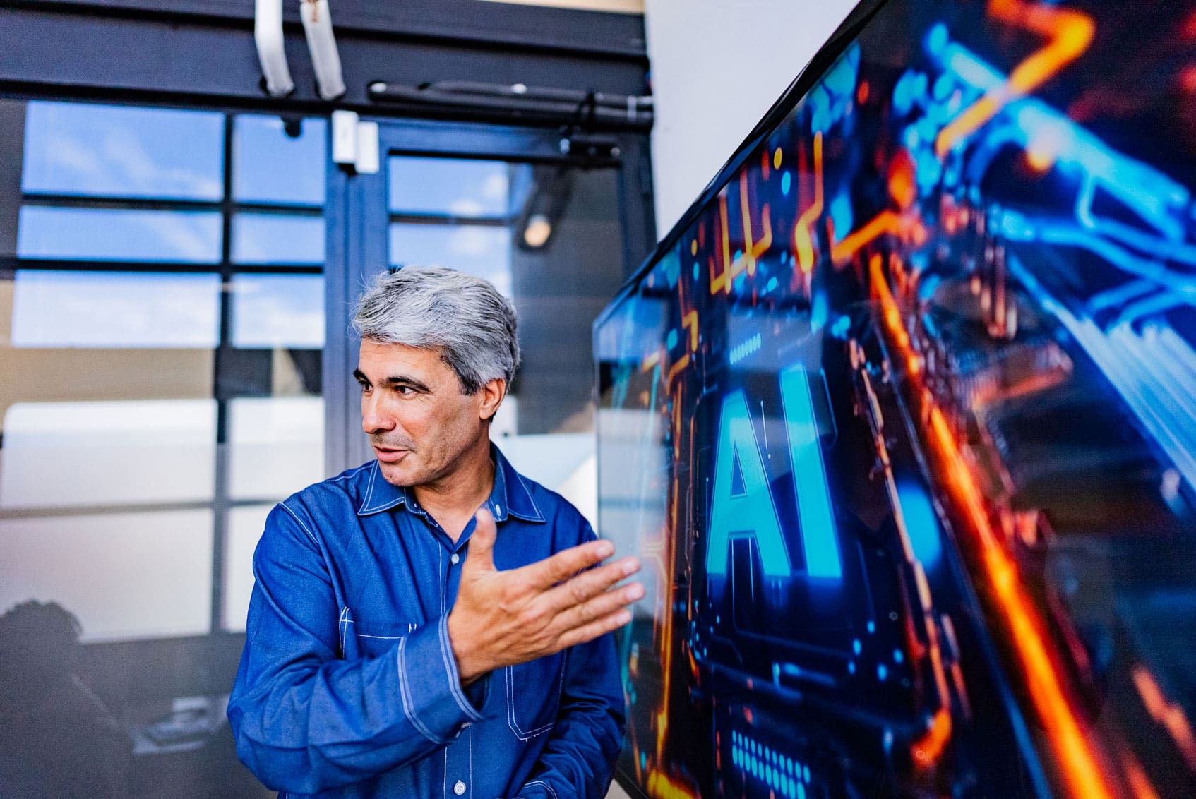 Man gestures near a screen in a law firm, displaying AI and digital graphics for strategic planning.