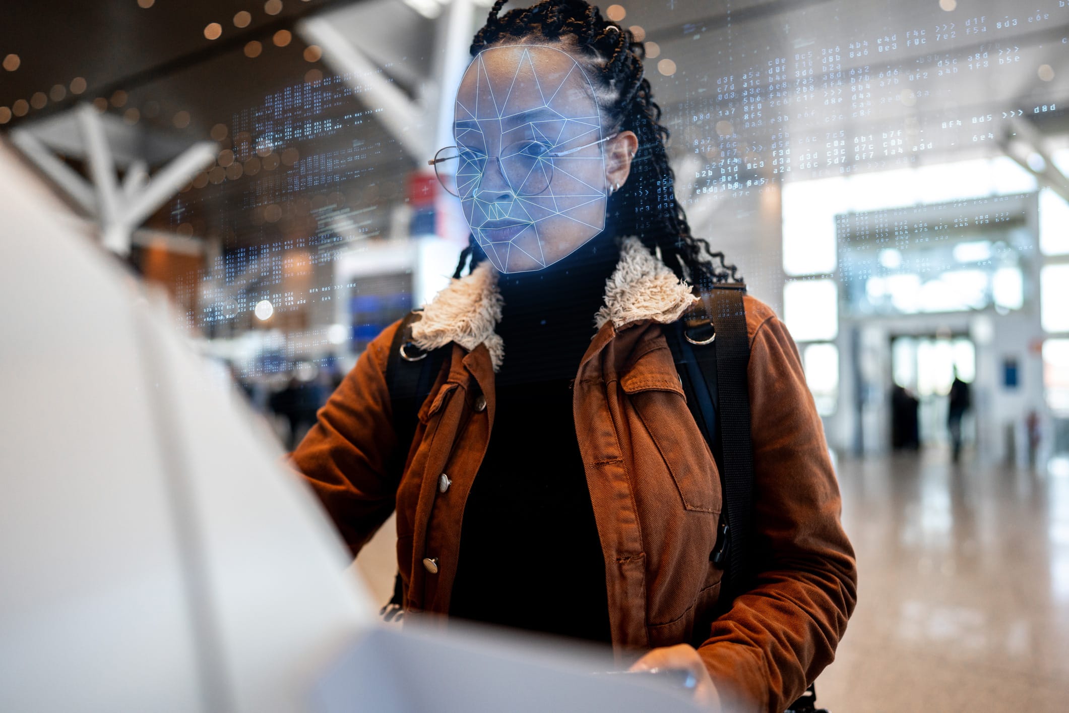 A woman uses a kiosk with facial recognition technology at an airport terminal.