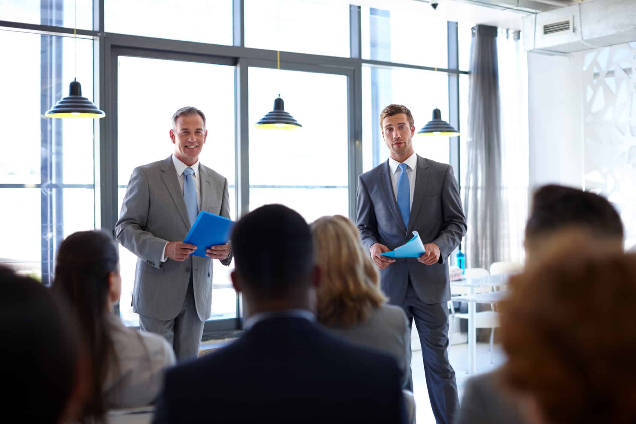 Two men in suits present on Airline Leadership Development & Talent Management to an audience.